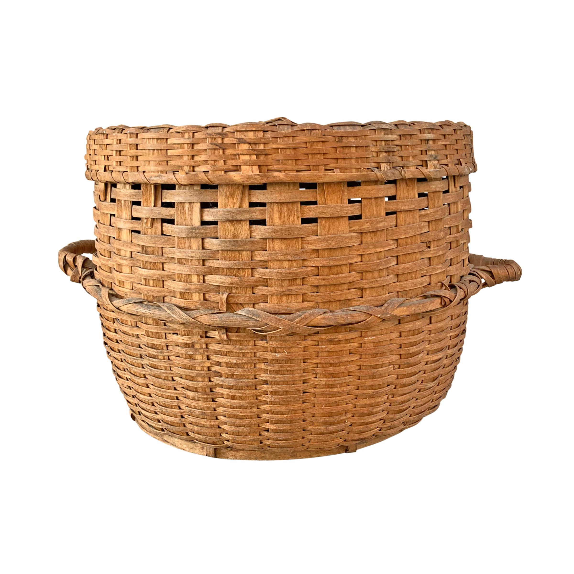 A monumental 19th century American ash and oak splint feather basket of fantastic size with two banded handles, a wide bentwood rib running around the belly of the basket, and a wooden ring base. Every farm in American had a feather basket where