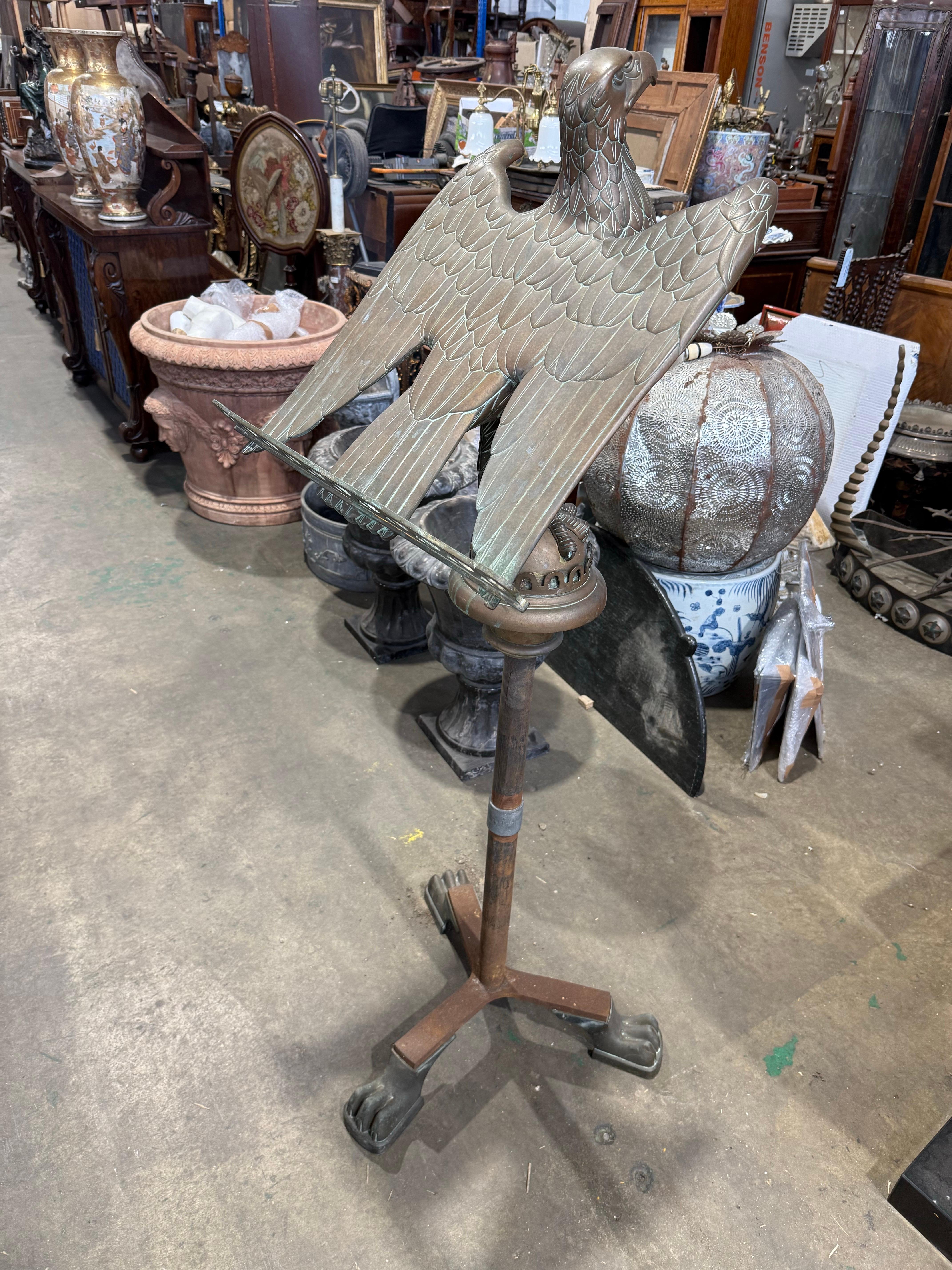 Un llamativo y sustancial atril eclesiástico de bronce del siglo XIX en el que aparece una majestuosa águila con las alas extendidas, símbolo de San Juan Evangelista. El águila se posa sobre una columna pedestal finamente detallada, que se eleva