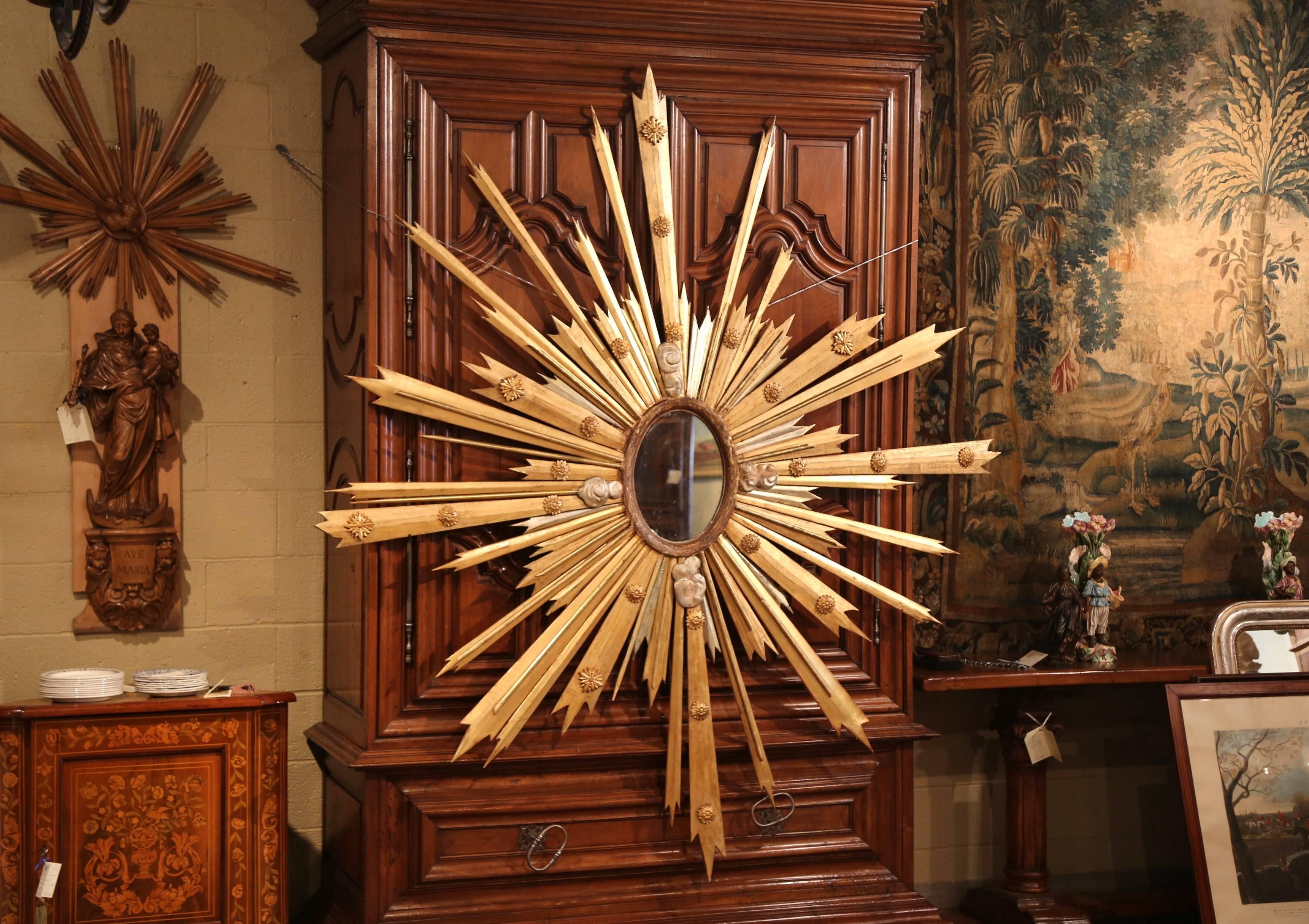 This important sunburst mirror was crafted in France, circa 1890. The monumental, stand-out piece features high relief carved decorative medallions with gilt and silvered sun beams. The piece has an oval centre mirror with its original mercury