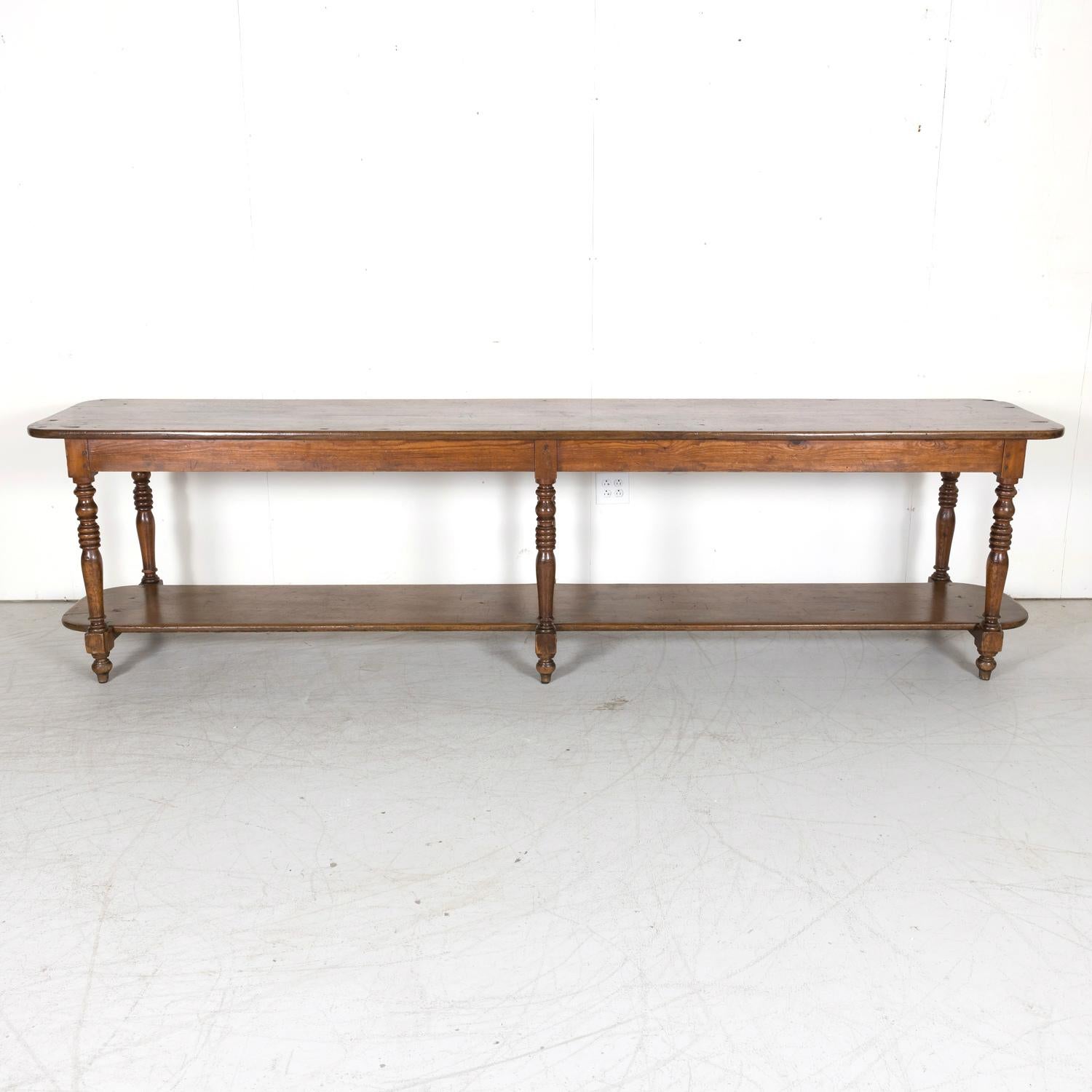 A monumental 19th century French Louis Philippe period table de drapier from a draper's atelier in Lyon, circa 1840s. Handcrafted of solid walnut with a pine skirt, this exceptional draper table features a large rounded edge two-plank top resting