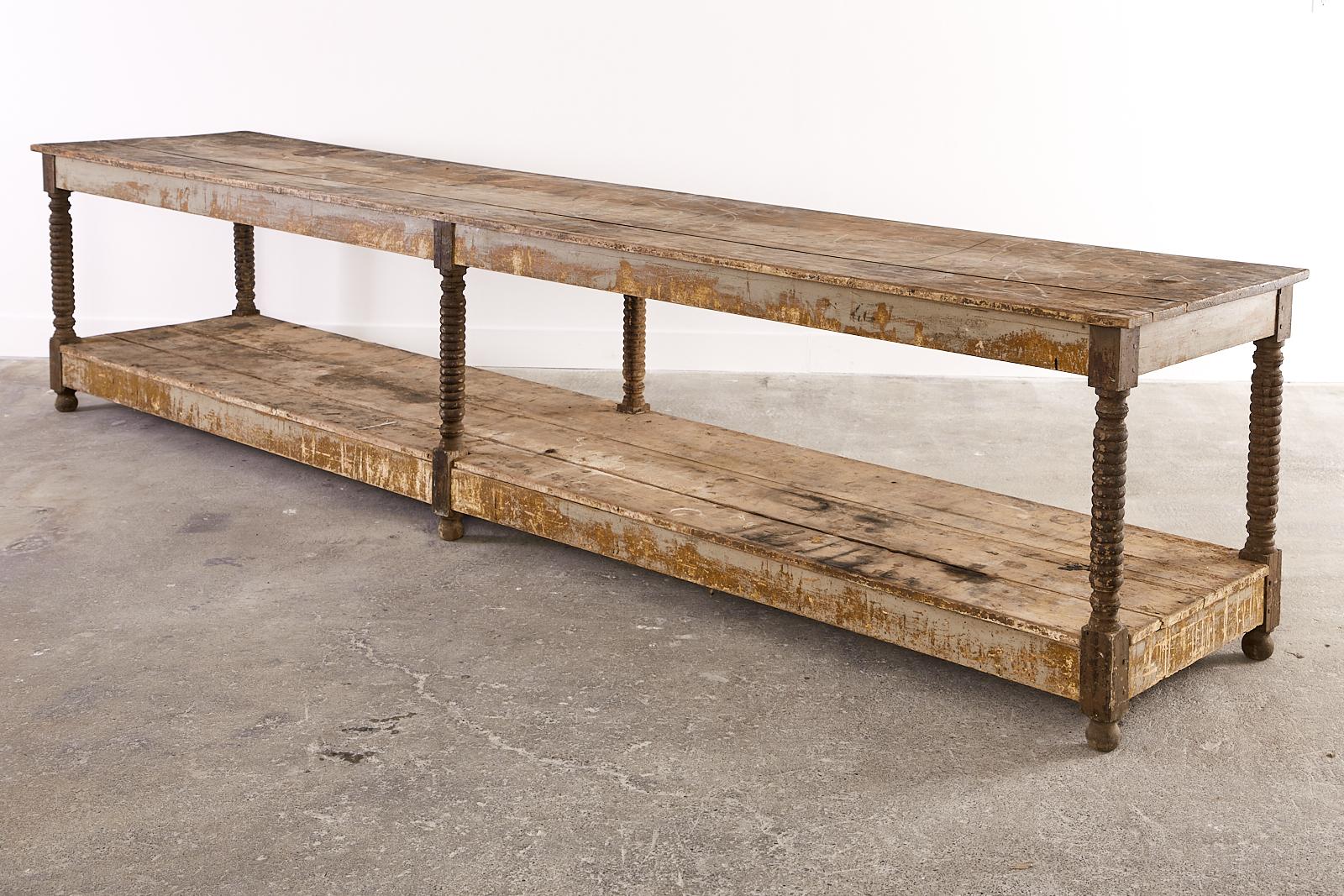 Fantastic monumental late 19th century French Drapers work table measuring 13 feet long. The massive 2 tier table features bobbin turned or spool legs ending with ball feet. The top is made of long planks 1 inch thick supported by an apron measuring