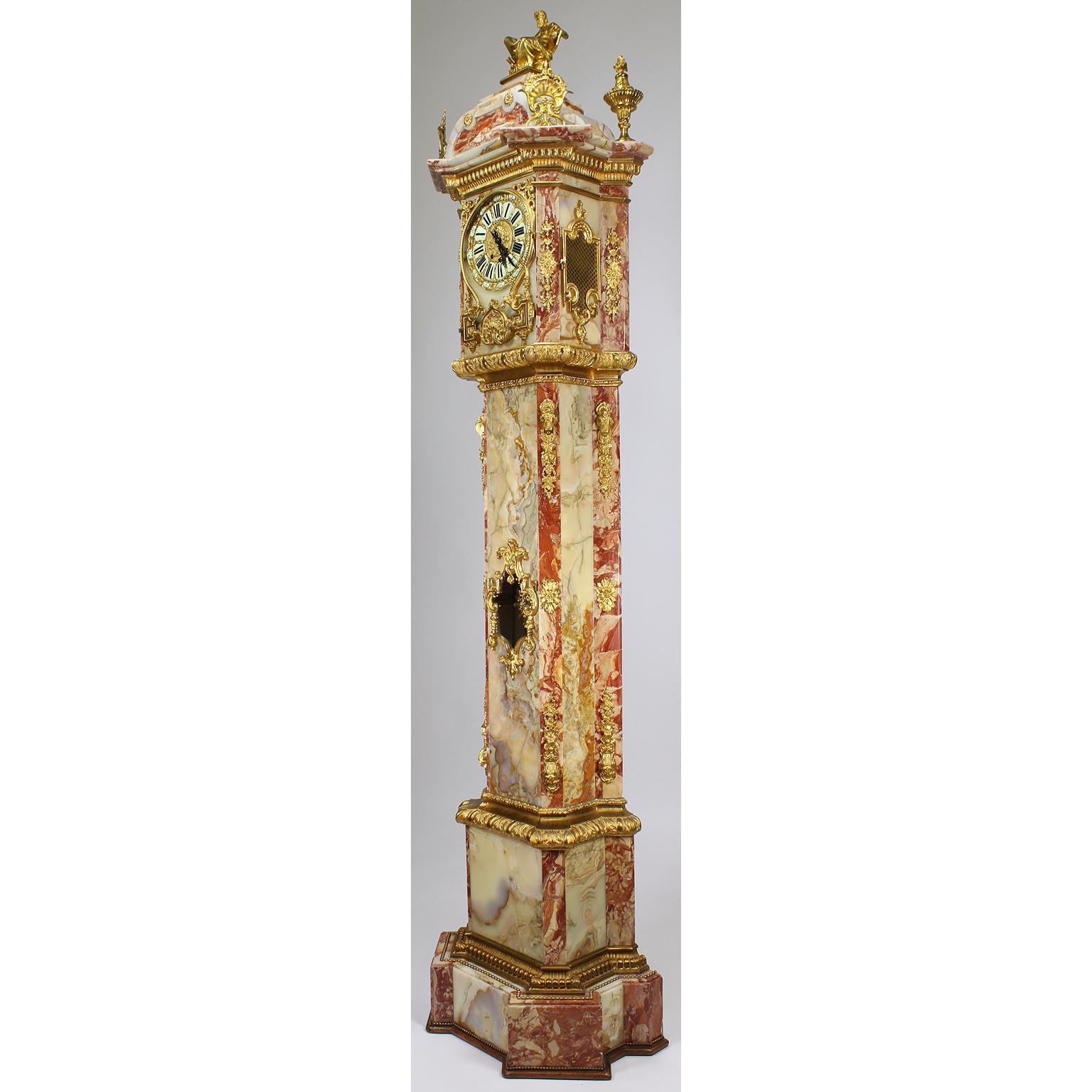 A monumental architectural French 19th century neoclassical Revival gilt bronze mounted beige and red onyx longcase grandfather clock. The very impressive clock-case surmounted by a figure of seated Classical male figure, the face opening to an