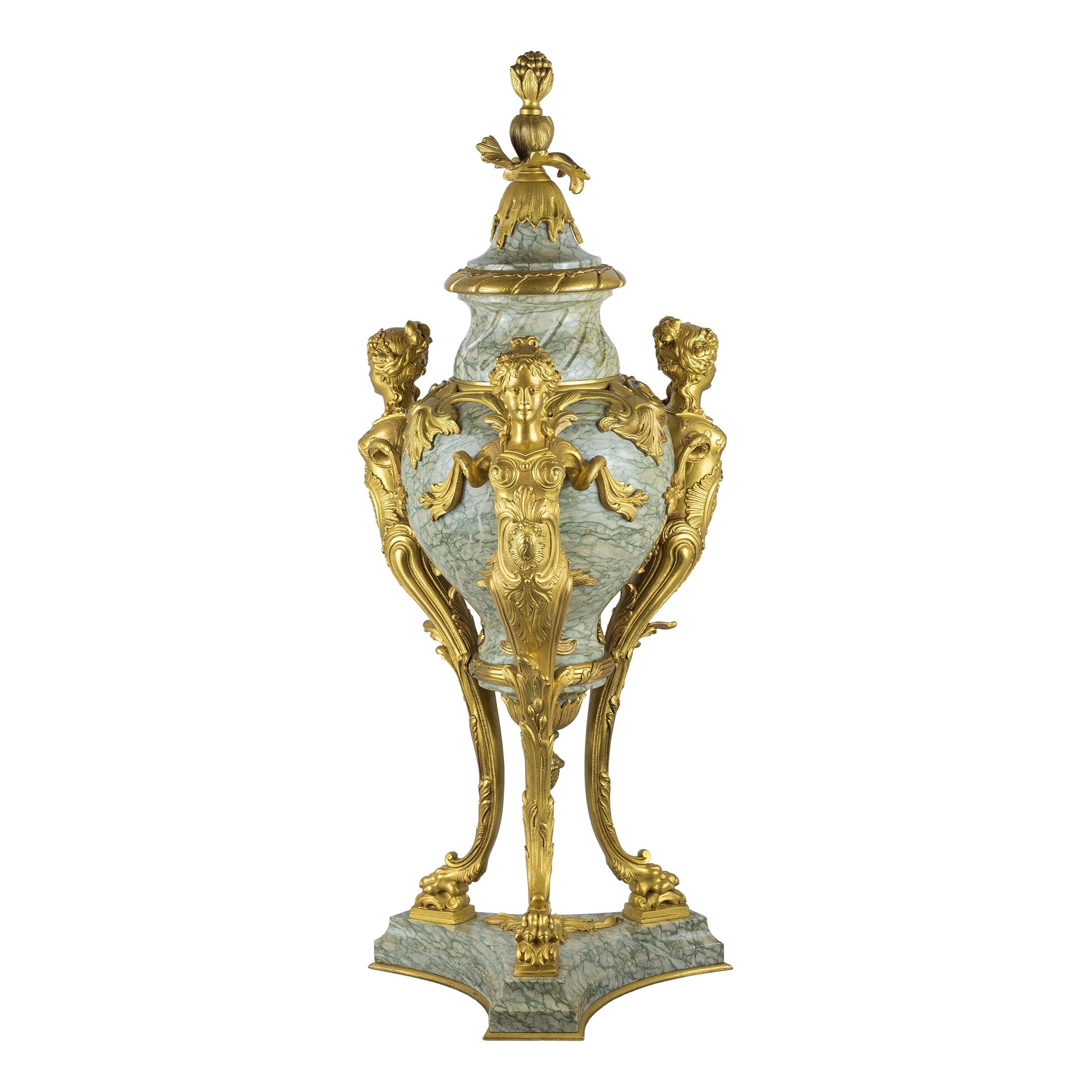 A monumental pair of baluster form gilt bronze-mounted Cipollino Verde mandolato marble urns.
The spiral fluted neck surmounted by an integral bell form cover terminating in elaborate fruiting finial, supported by three finely casted Caryatid