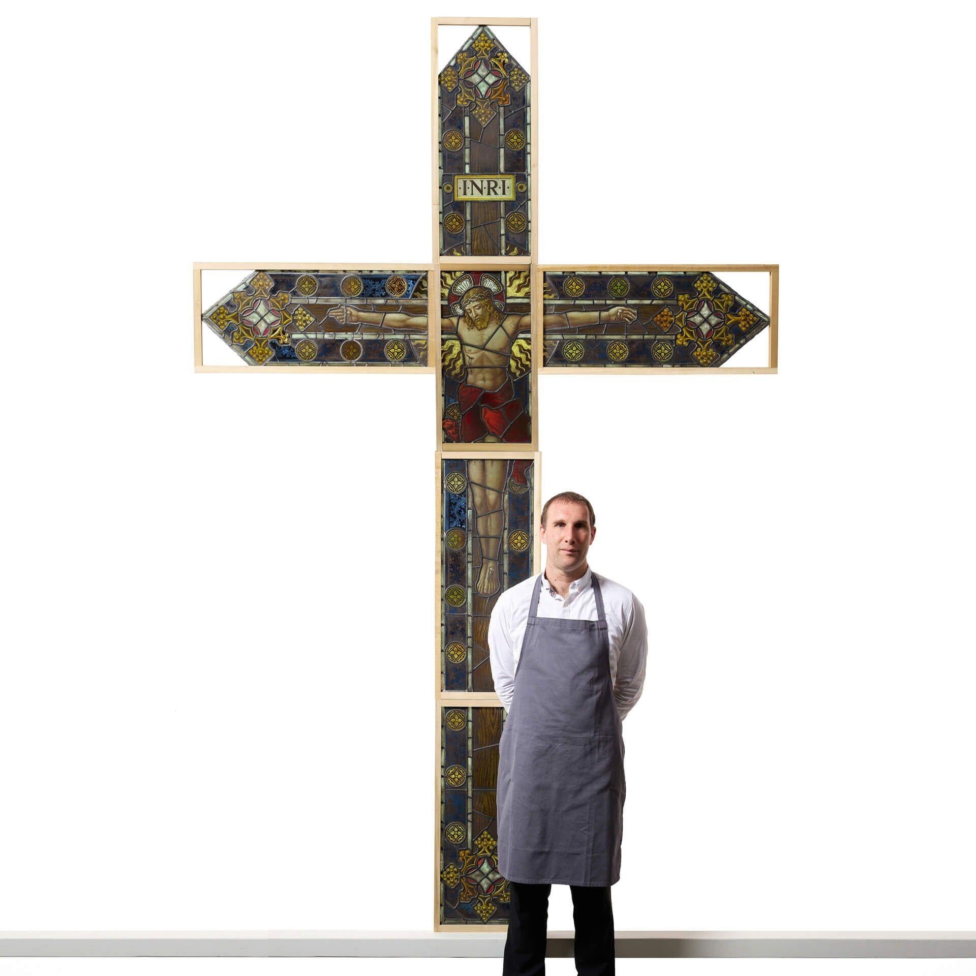 A monumental antique 19th century stained glass crucifixion window depicting Jesus on the cross below the Latin inscription ‘INRI’. This impressive religious stained glass window comprises of 6 individual glass panels, together creating a huge