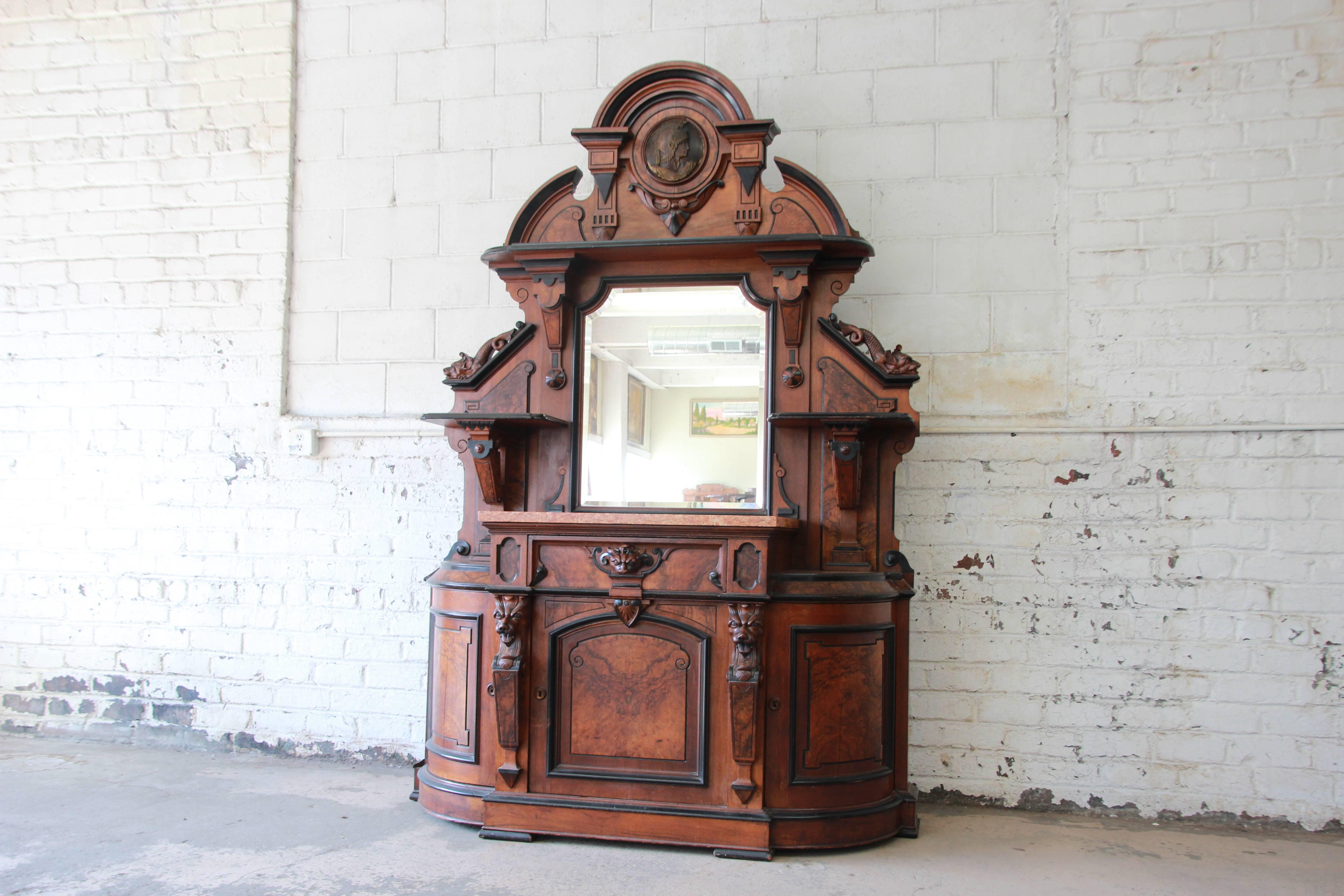 Offering a rare and outstanding monumental 19th century Victorian sideboard. The sideboard features fantastic carved wood details with a dragon motif and gorgeous burled walnut wood grain with ebonized trim. It has a very nice original