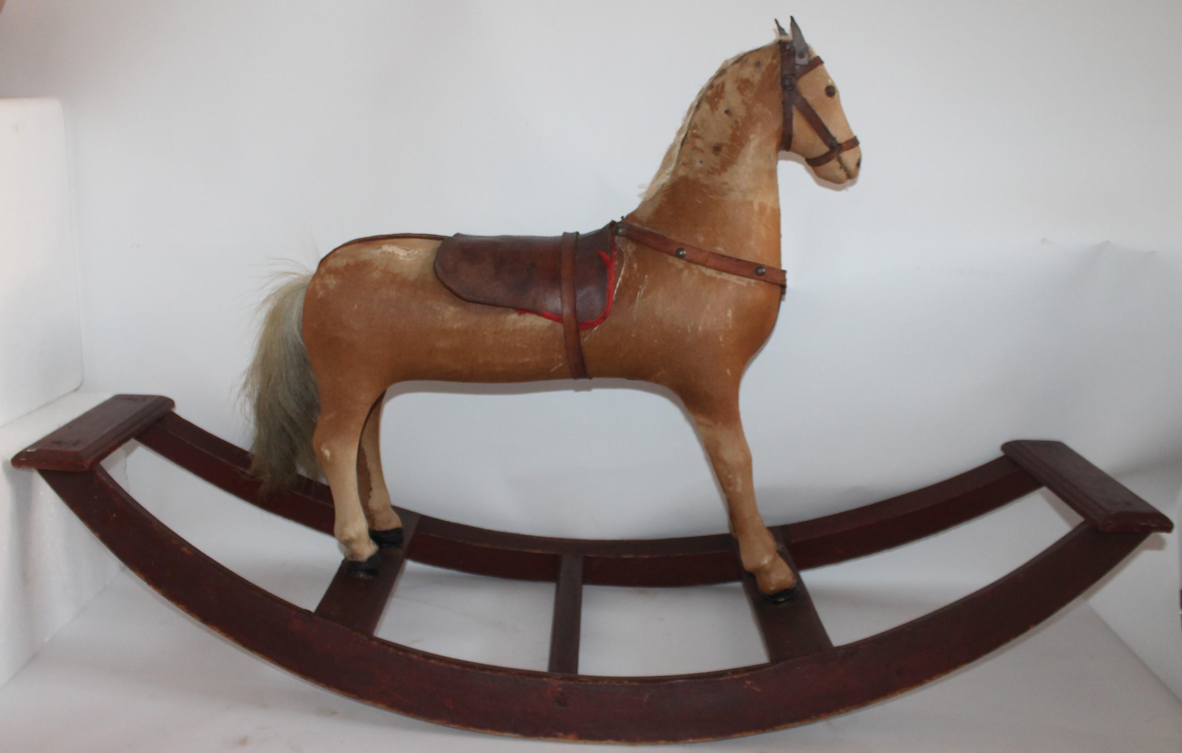 Ce très beau cheval à bascule de campagne n'a pas seulement un aspect fantastique et une peinture d'origine, il est aussi solide et résistant. La peau de poney est usée ainsi que la selle mais tout est en place.
