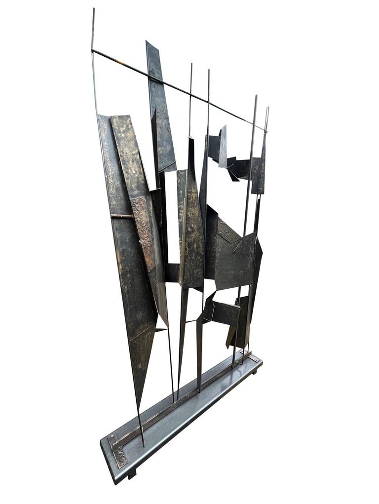 A massive brutalist sculpture from the Paul Evans & Harry Bertoia Era circa 1970's. It consists of welded steel construction with some brass and bronze overlays. Originally this had a direct to floor mounted installation. The base was built for the