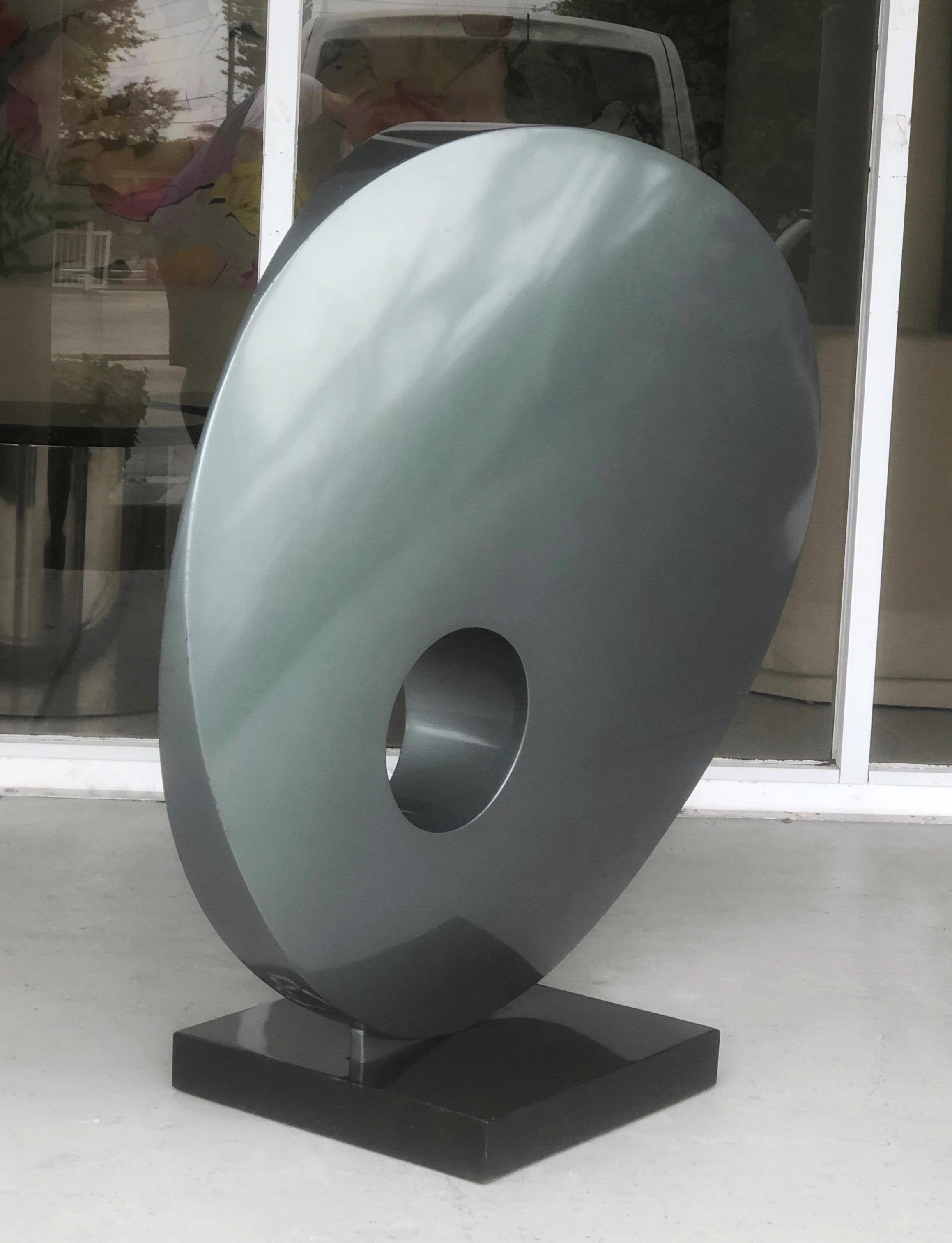 A very large sculpture. Suitable for indoors as well as outdoors. A very clean abstract design, round in shape, it is wider on one side becomes thinner on the other side, it also has a see through round area a la Barbara Hepworth. It is mounted on