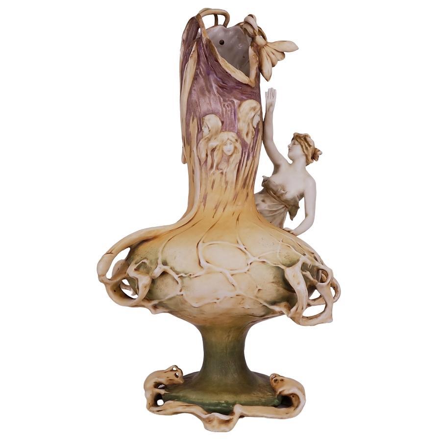 Monumental, museum quality, signed Reisner Stellmacher & Kessel Art Nouveau porcelain vase / lamp. This vessel features an organic footed body with foliage and floral designs mounted by a full-bodied maiden figure entranced by the two main flower /