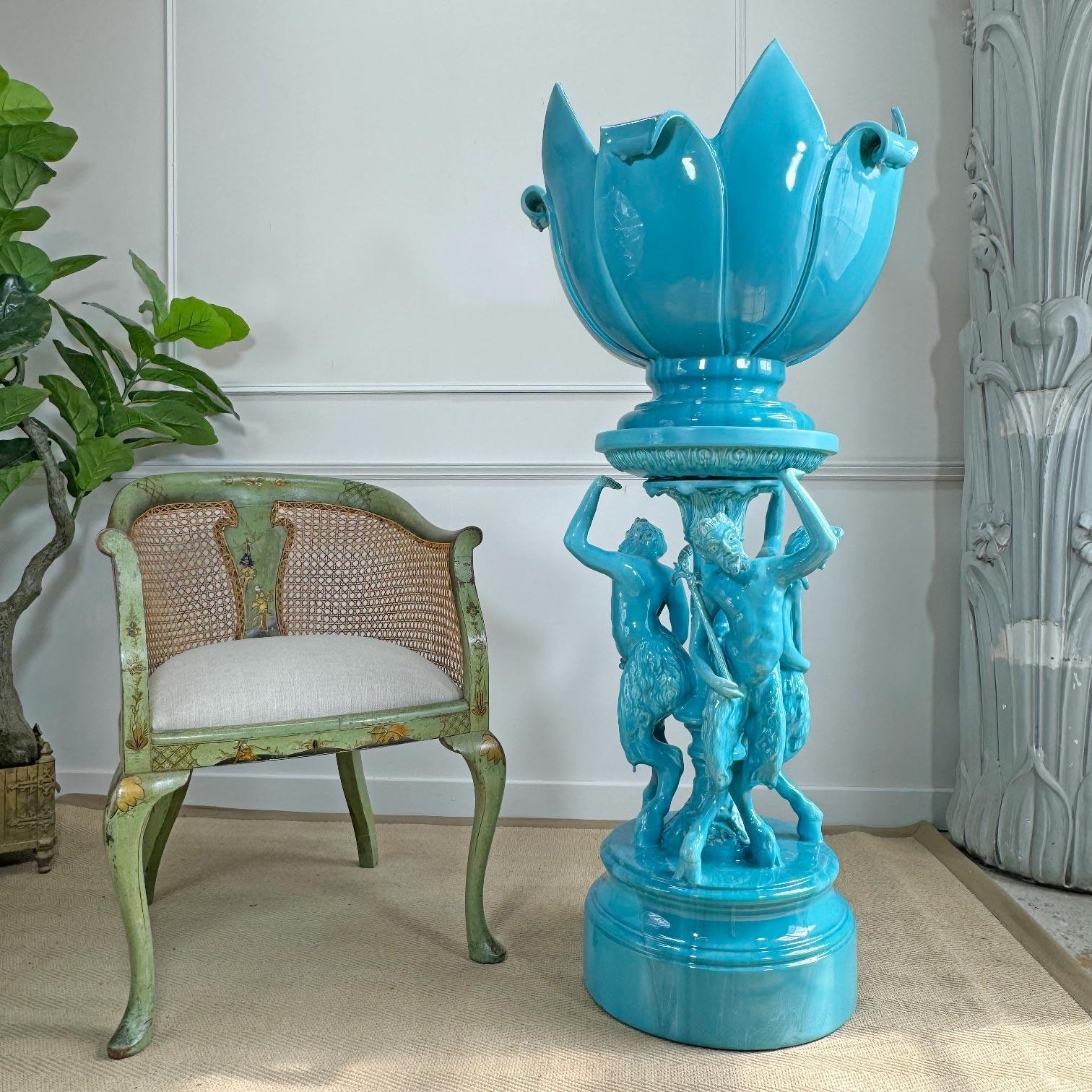 A truly outstanding Art Nouveau ceramic planter and stand in blue glazed faience, modelled as a trio of dancing satyr, complete with thyrsus in hand, their hoven feet firmly on the base of the stand, each with a raised arm holding aloft the huge,