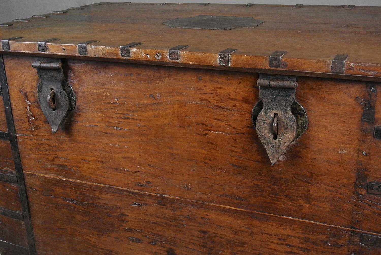 Un baúl de plata o de dote muy inusual y muy grande, hecho enteramente de teca maciza y gruesamente tallada, con grandes colas de milano a la vista y con esquinas de hierro atadas, encuadernaciones de hierro, aldaba original en forma de corazón