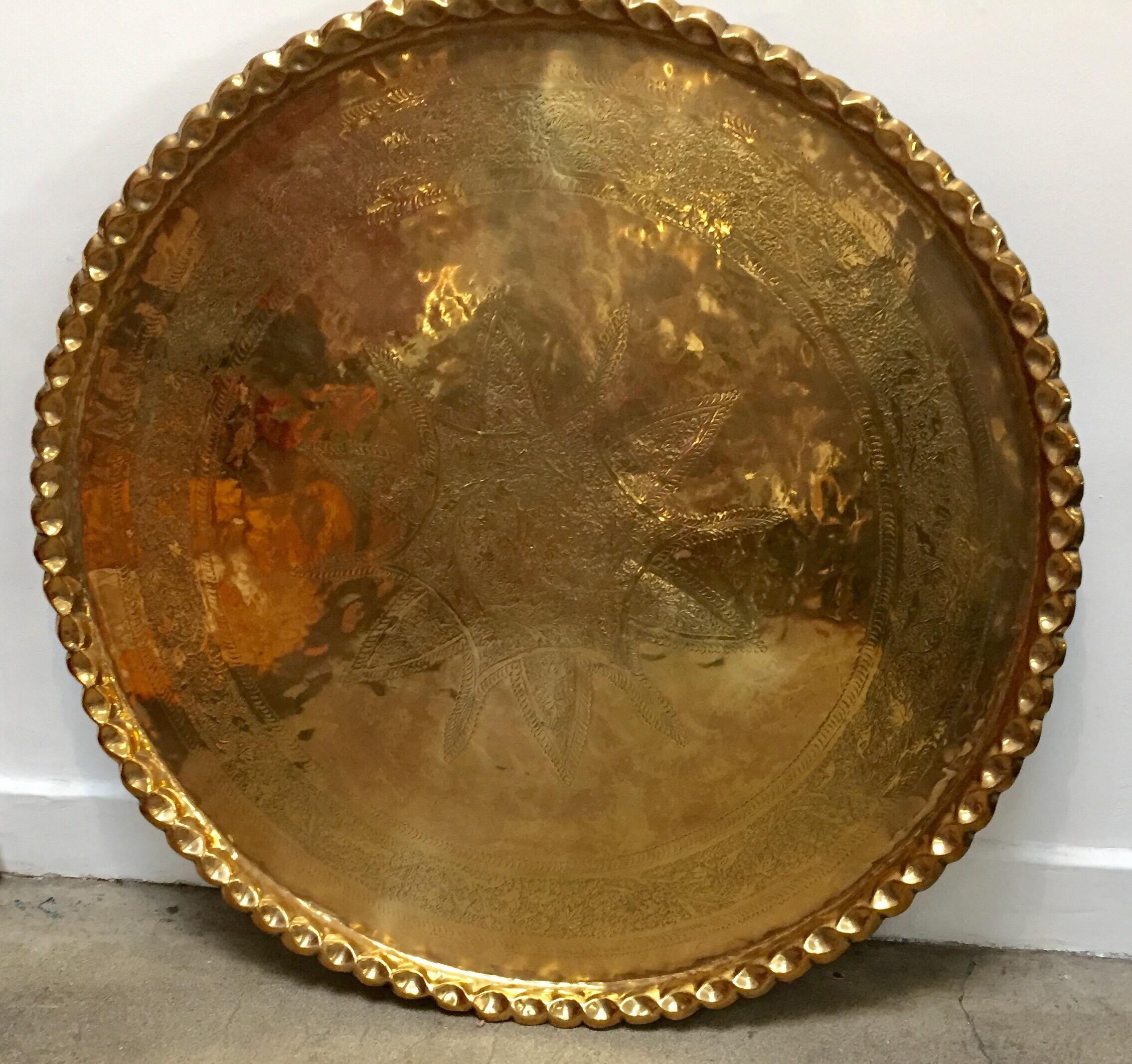Monumental Moroccan Metal brass tray platter.
Polished decorative metal brass tray with very fine intricate designs.
Hand-hammered and chiseled in floral Moorish style with a large lotus flower in the middle, pie crust border.
Heavy brass metal