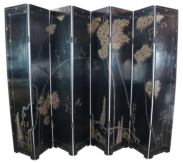 Monumental antique Chinese black lacquer folding screen or room divider featuring a golden landscape of the Eight Immortals among a sea of clouds above pagodas, boats and a lighthouse. Surrounded by a boarder of antique pots and vessels, urns and