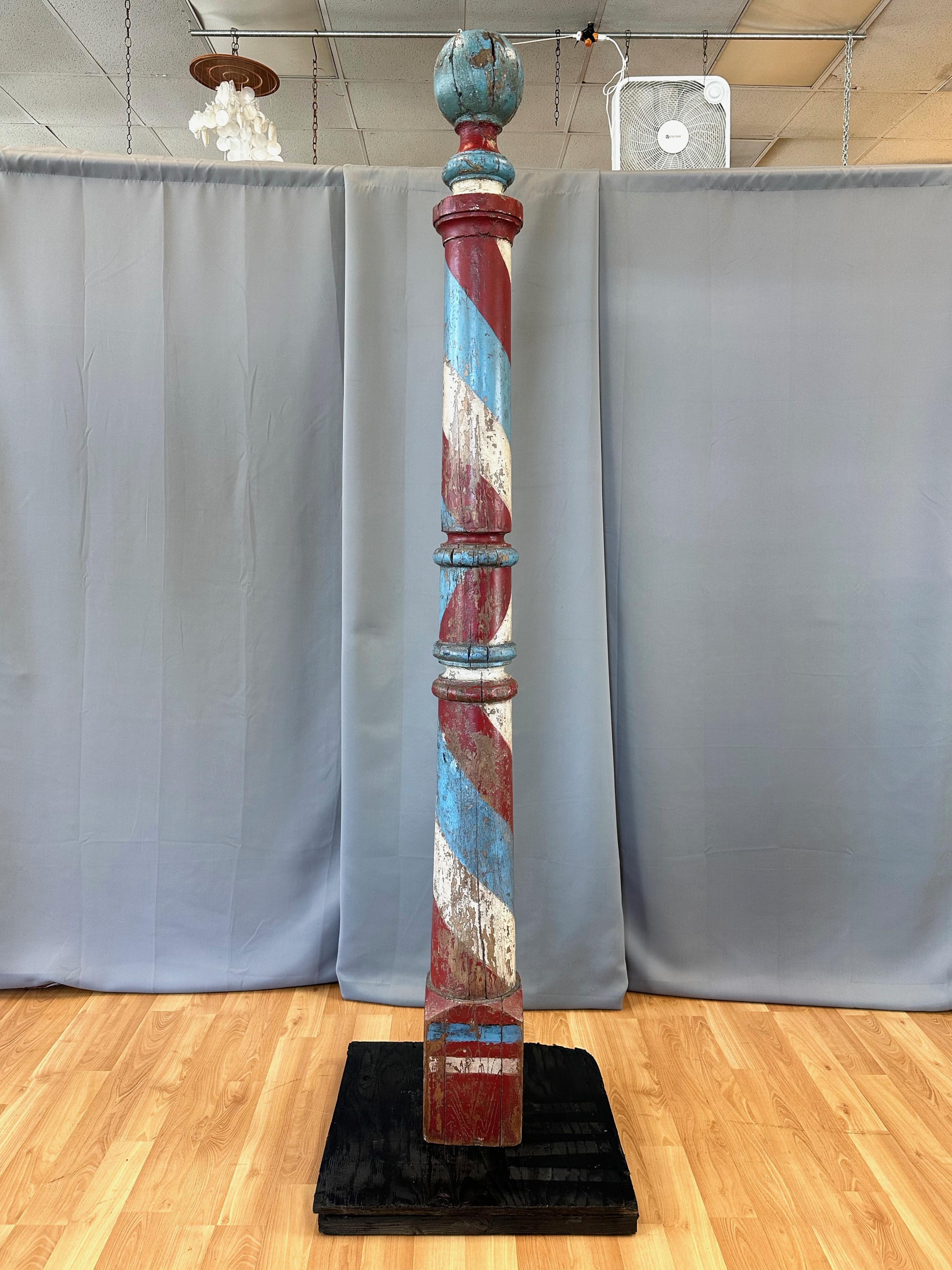 An uncommon and towering seven-and-a-half-foot tall circa 1875 American painted turned wood barber pole trade sign.

Very impressive in both its rarely seen size and hand-crafted execution, with its turned wood form featuring a ball top and