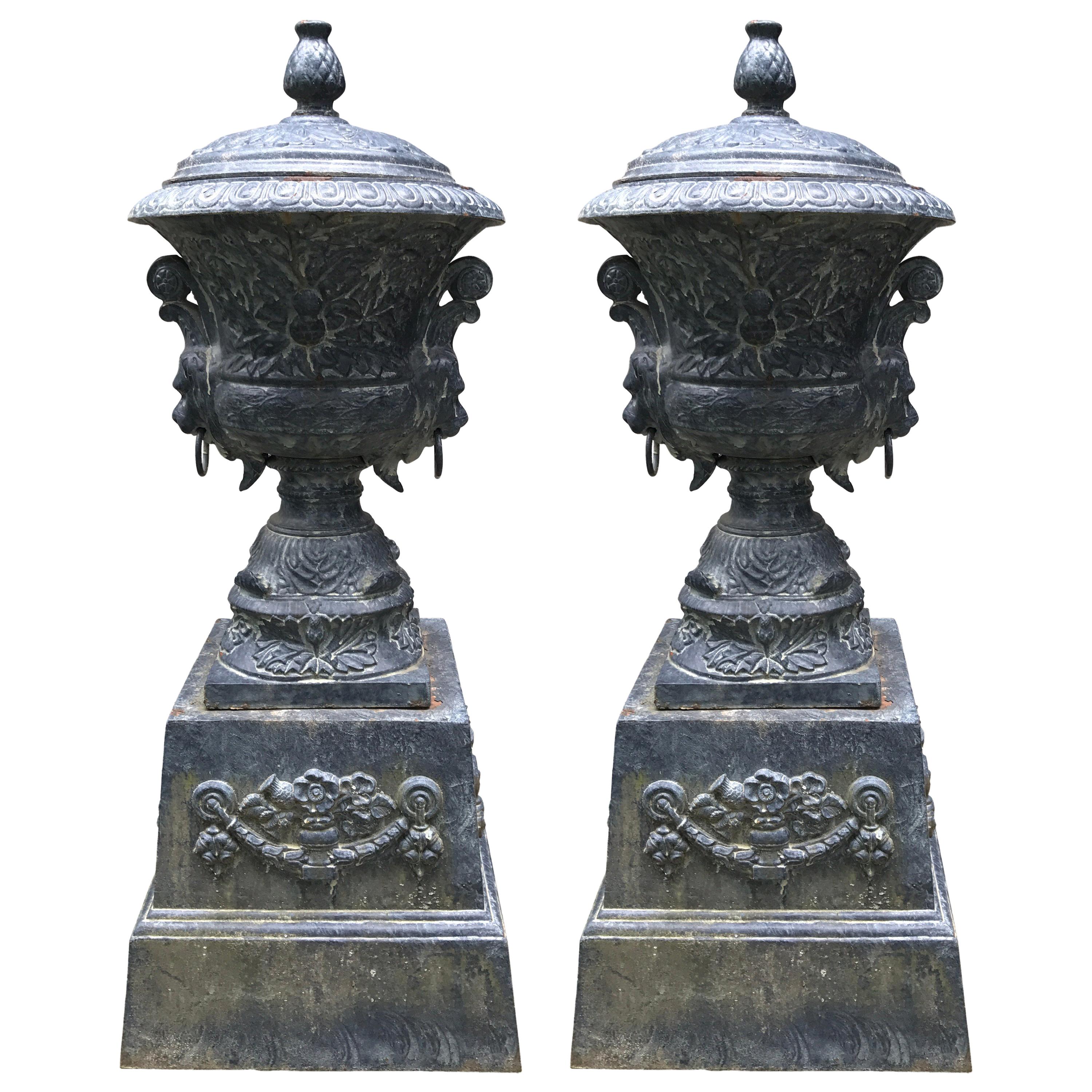 Monumental Antique Covered Cast Iron Urns on Plinths and Lion Head Handles, Pair