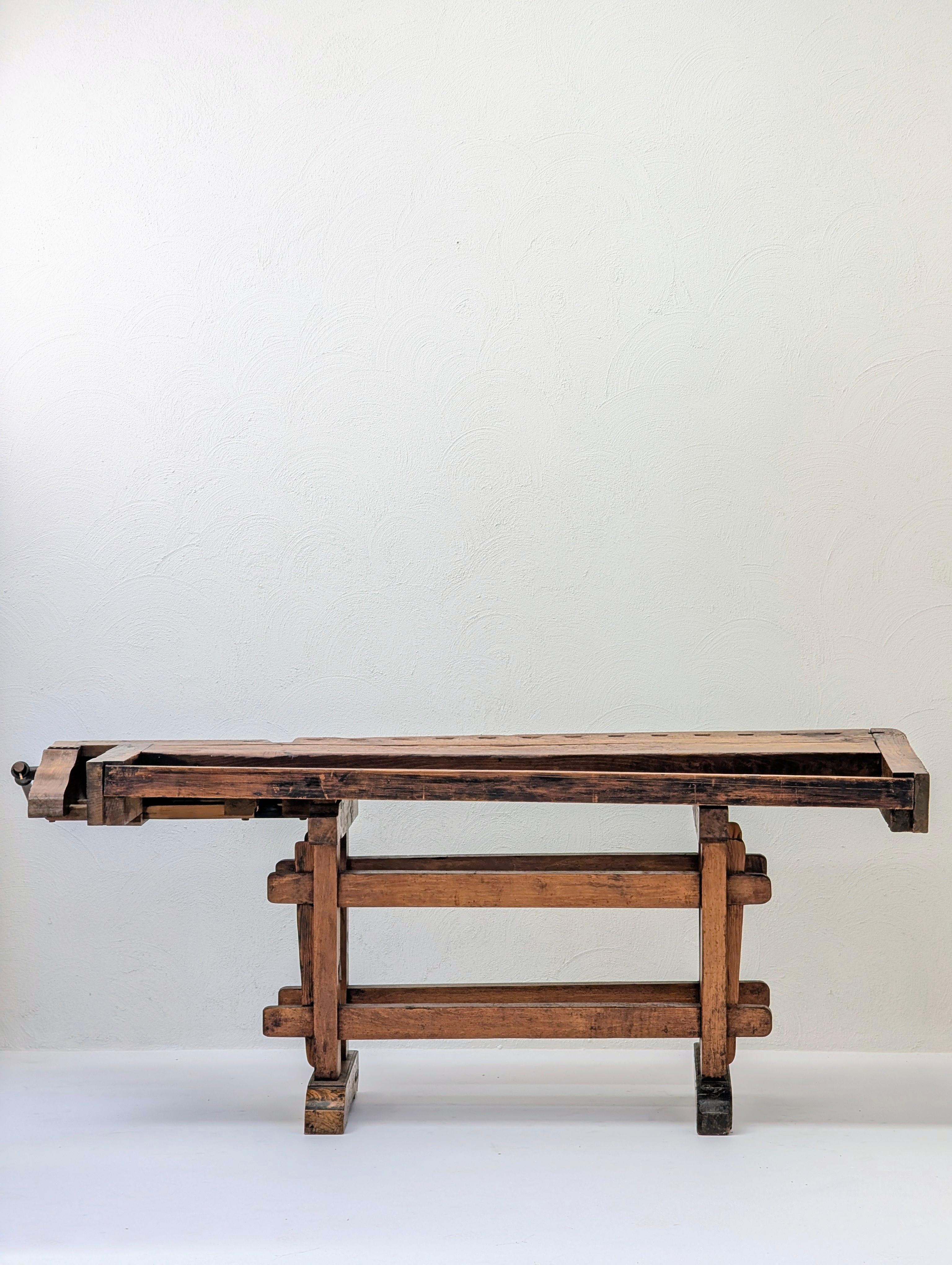 An exceptionally character-rich antique European woodworking bench, dating to the early 20th century.

Crafted from solid, heavy timbers (likely European oak), this piece tells the rich story of a lifetime of artisanal use. Its 