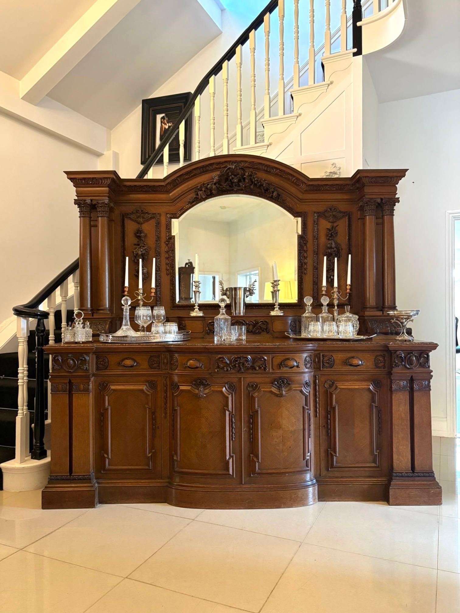 Monumentale credenza vittoriana di qualità intagliata in quercia di Maple & Co. con uno schienale a specchio a forma di arco e bordo smussato con intagli di qualità in quercia intagliata sostenuti da quattro colonne corinzie intagliate e sollevate