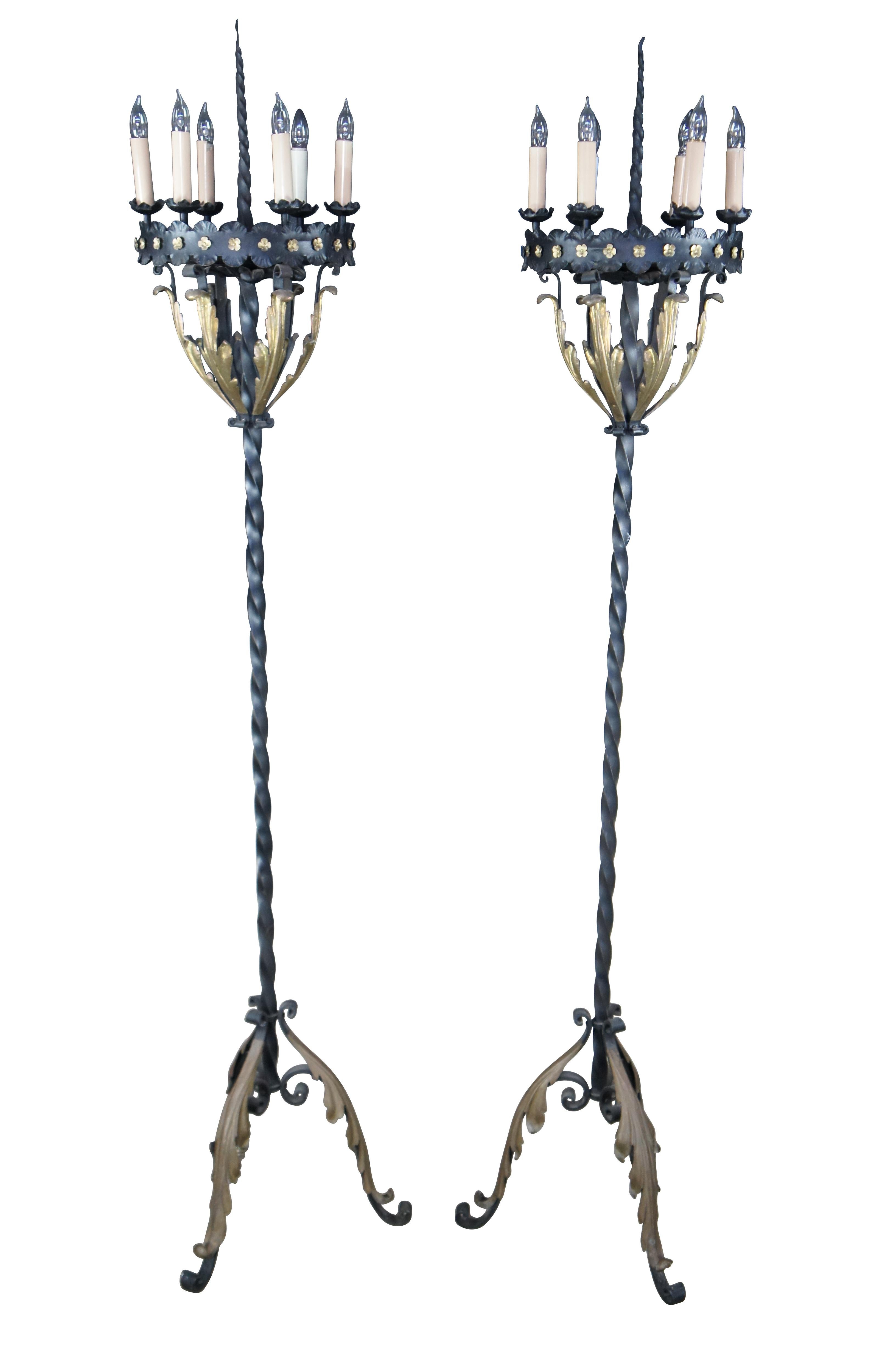 Early 20th Century pair of Spanish Revival palace sized torchiere candelabra floor lamps.  Made from black twisted iron with gold acanthus trim and floret accents.  Each lamp has six candlestick posts centered around a twisted iron spire.  The