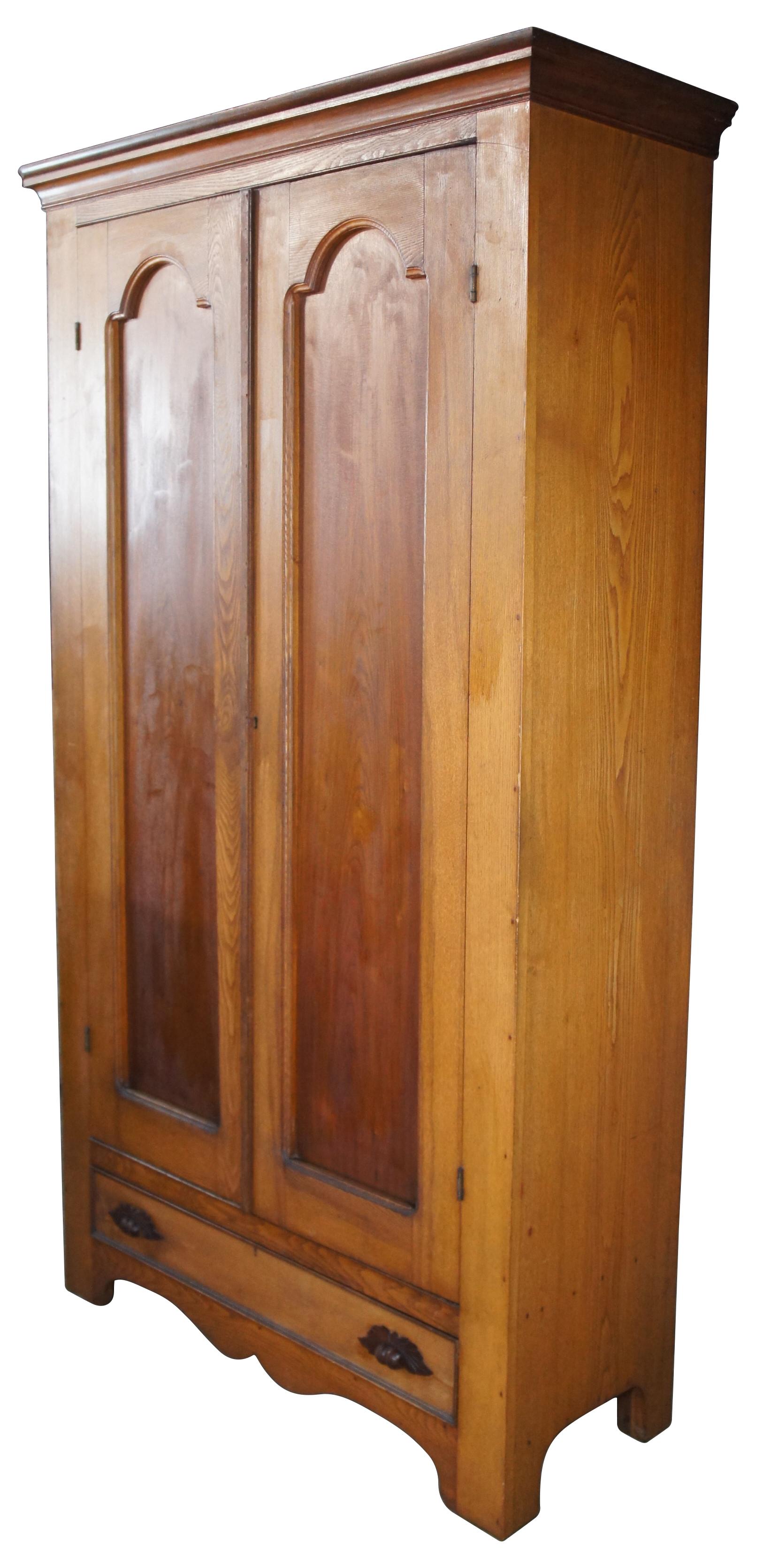 A large and impressive late Victorian clothing wardrobe or hall tree. Made from oak with large double doors that open to a shelf and hooks for hanging garmants. Features a large lower hand dovetaile drawer with classic fruit and nut pulls. Marked