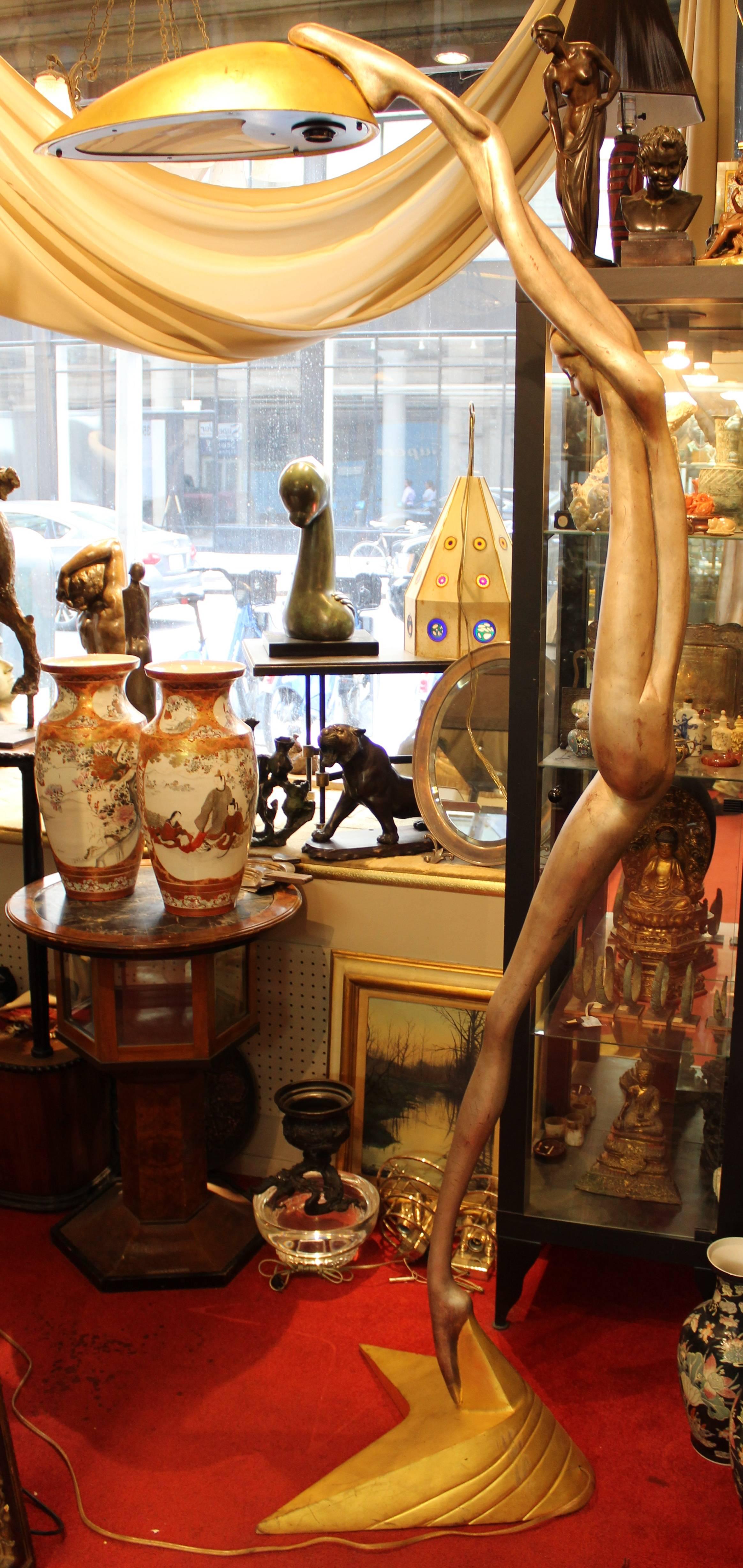 Une paire de lampadaires monumentaux de style Art Déco en forme de nus féminins allégoriques, chacun tenant une source de lumière avec une jambe et un bras levés. La paire est faite de bronze massif argenté et doré et date des années 1960-1970.