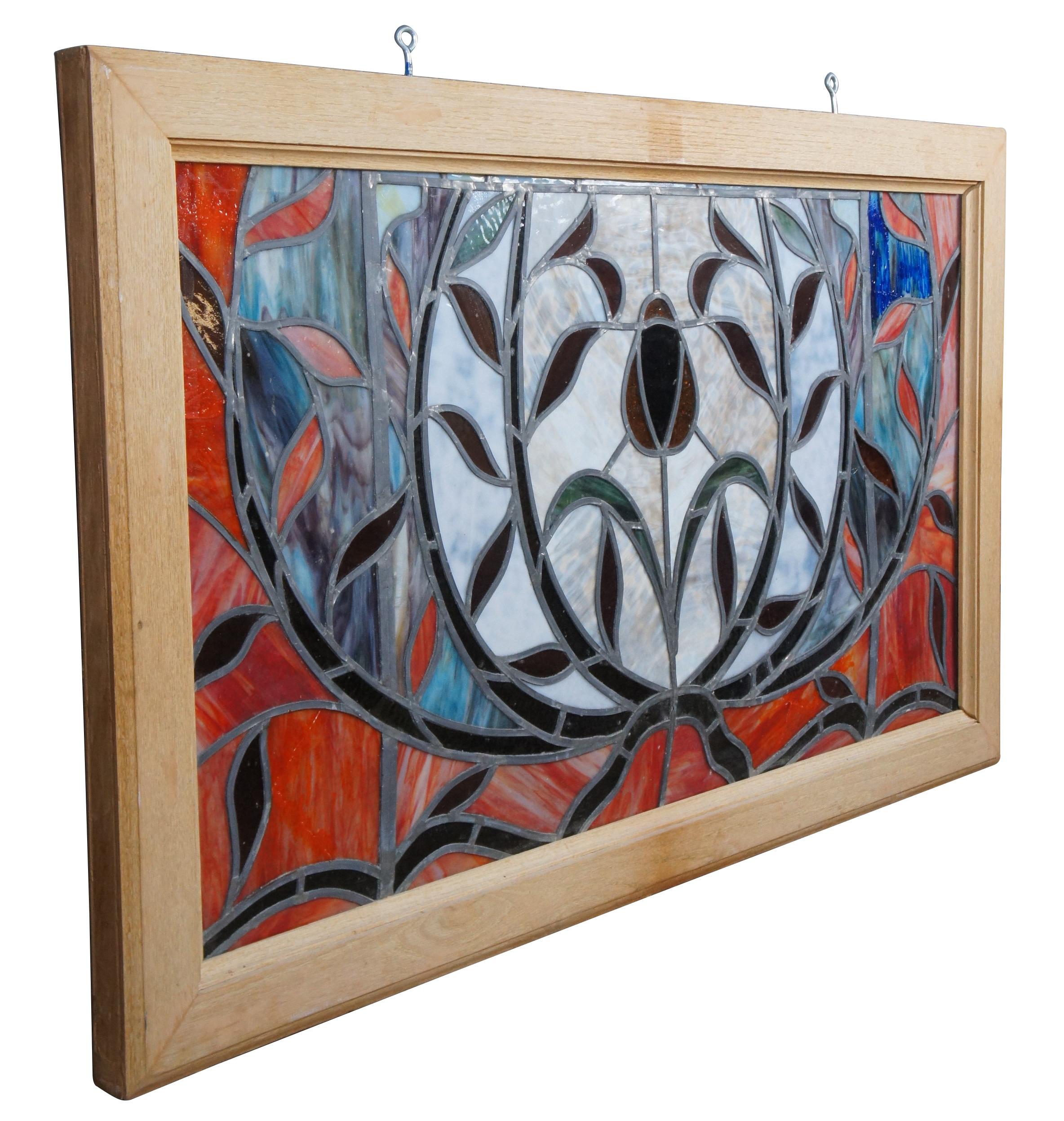 Late 20th century leaded stained glass window hanging panel. Features a field of red with accents of amber, blue and purple. At the center is a rose with foliate surrounds. Framed in a heavy oak with two eye hooks along the top for hanging