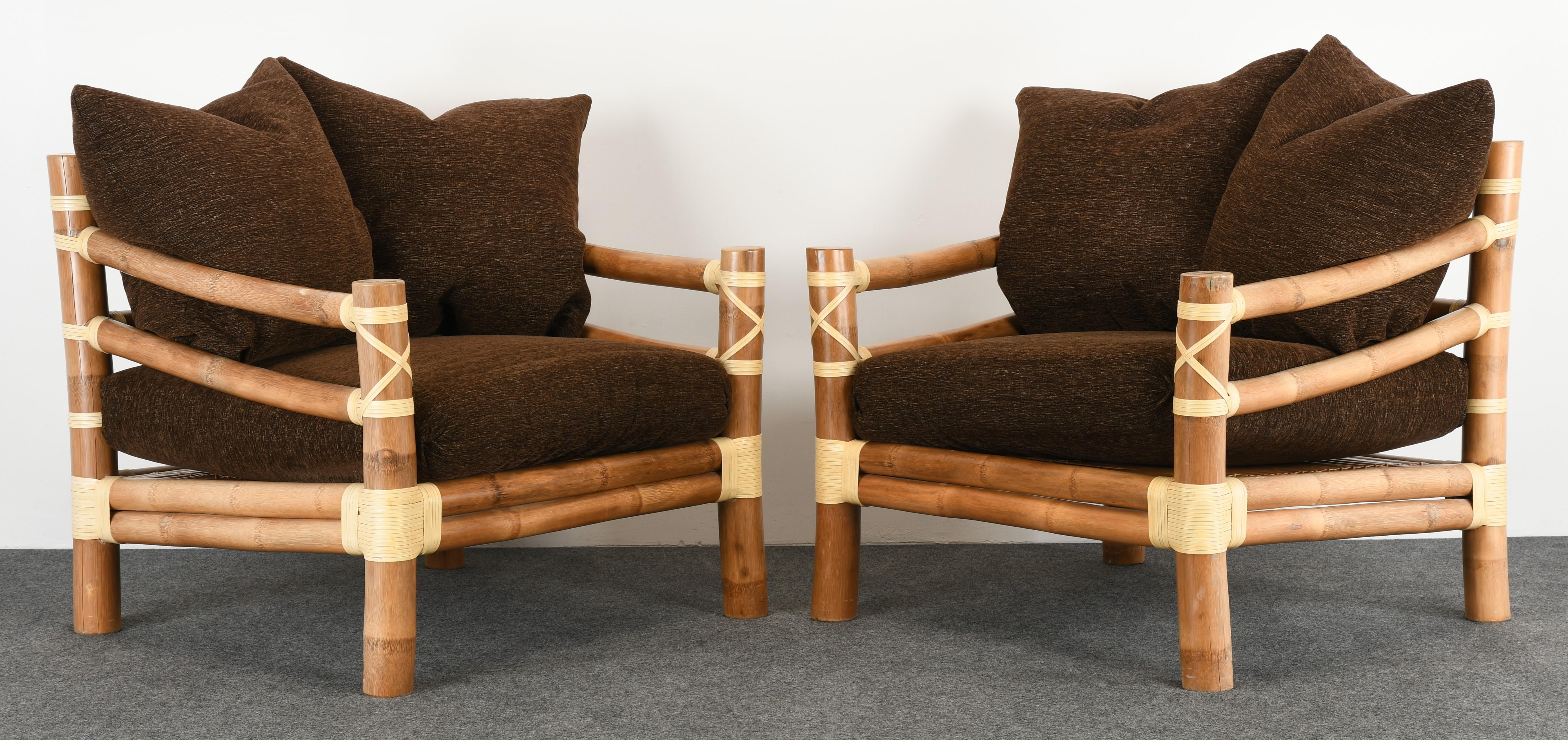A wonderful pair of large-scale bamboo lounge chairs wrapped with leather accents. These chairs are reminiscent and have the quality of McGuire Furniture. The cushions add a lot of comfort and are overall in good vintage condition. The leather