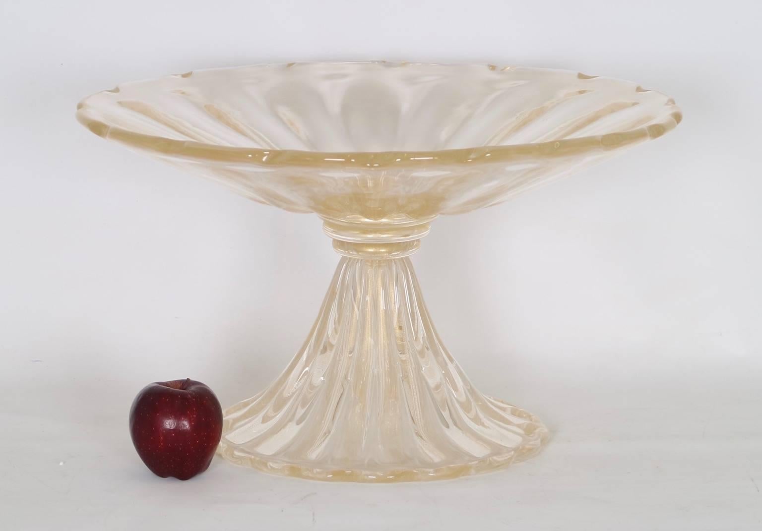 Monumental Murano Hollywood Regency glass footed center bowl by Barovier. The clear glass is profusely infused with gold dust. This piece is in excellent vintage condition and has wear consistent with age and use.