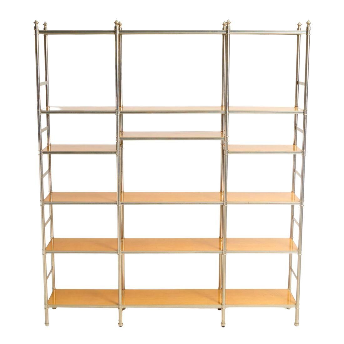 A brass Billy Baldwin style etagere with wood shelves.  The etagere structure is polished brass with finials to finish the four top corners.