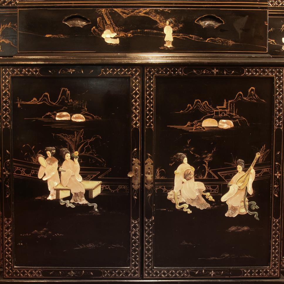 Monumental black lacquer chinoiserie cabinet with a pagoda top in three sections. Beautifully decorated with cream and gold figural Asian scenes. The top has four glass doors and there are four concealed doors below.