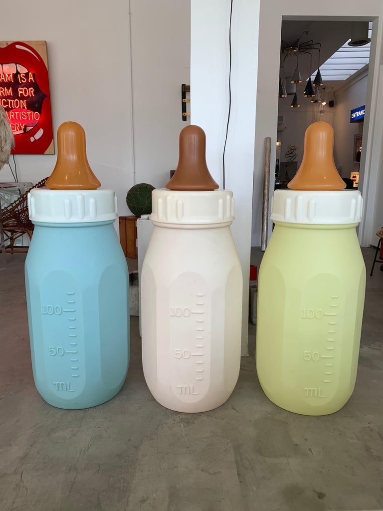 Gigantic baby bottle made in the 1970s. Hard plastic bottle with removable top and rubber nipple. Blue bottle with ounces on one side and milliliters on the other. At three and a half feet tall and 15