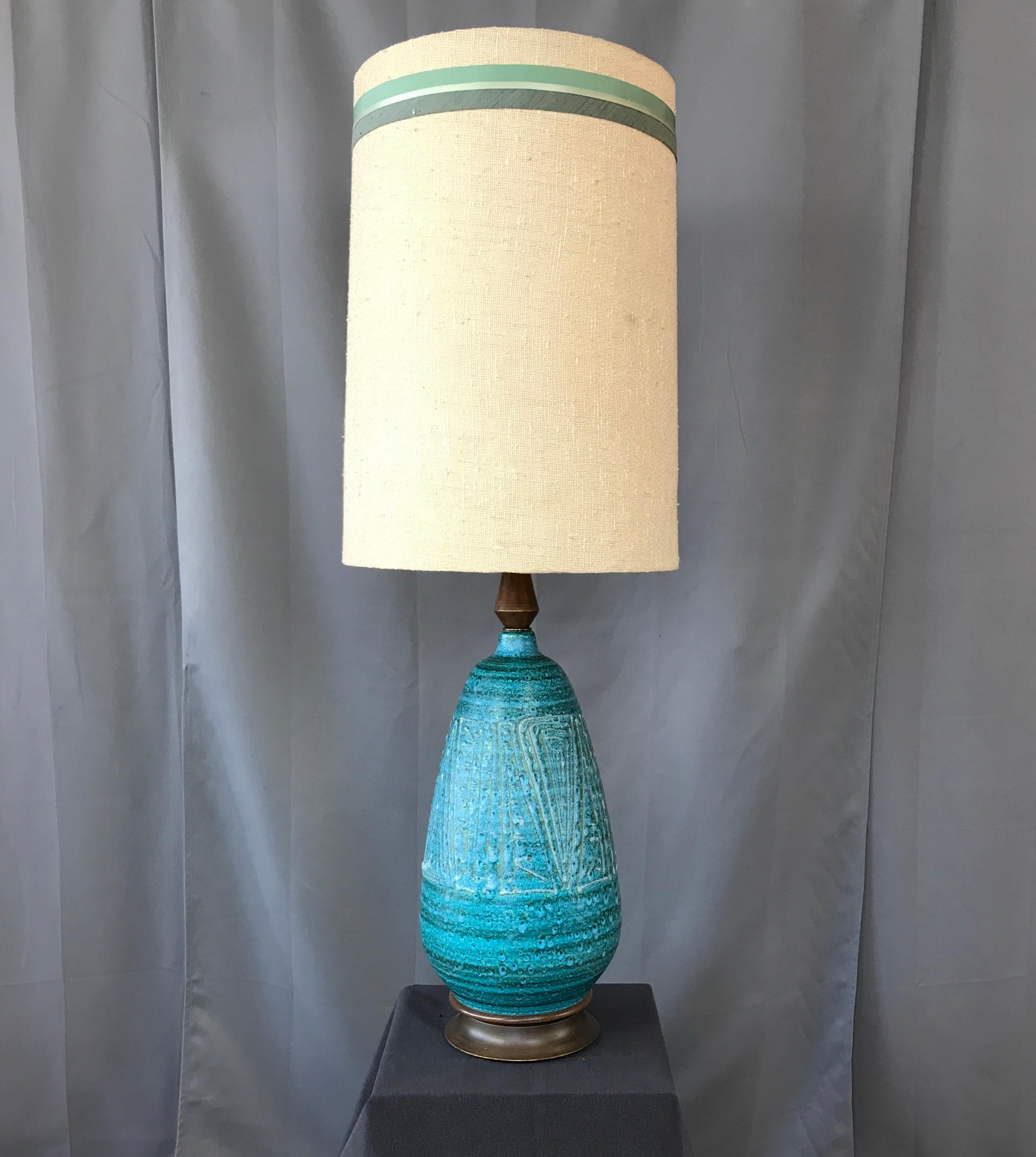 Offer here is a monumental circa 1950s ceramic lamp. The lamp's large body is mostly blue with hints of green, framed by a large walnut stain wood base and neck. A freeform and textured design on the ceramic. No markings, but sure has that Italian