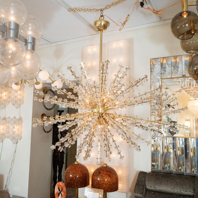 Monumental brass starburst chandelier featuring glass nugget encrusted rays.