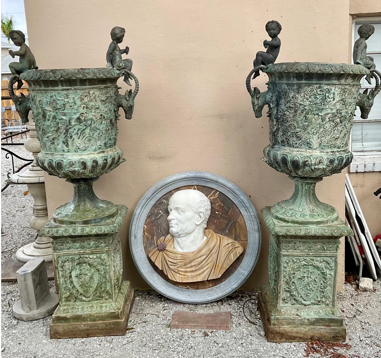 Coppia di vasi in bronzo con figure classiche francesi di grandi dimensioni dei primi anni del XX secolo. Le fioriere sono caratterizzate da teste di cervo su ciascun lato sotto a cherubini seduti. Le teste di cervo potrebbero essere considerate