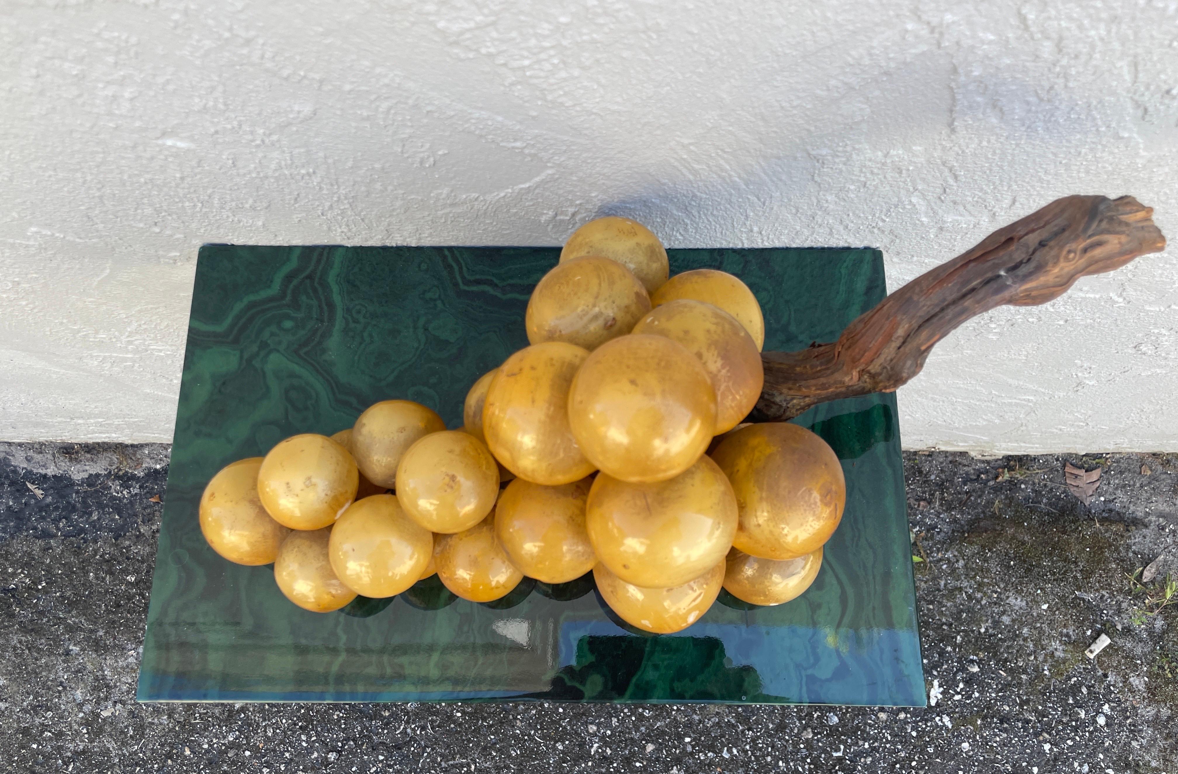 Racimo monumental vintage de uvas amarillas de alabastro italiano sobre rama de madera.