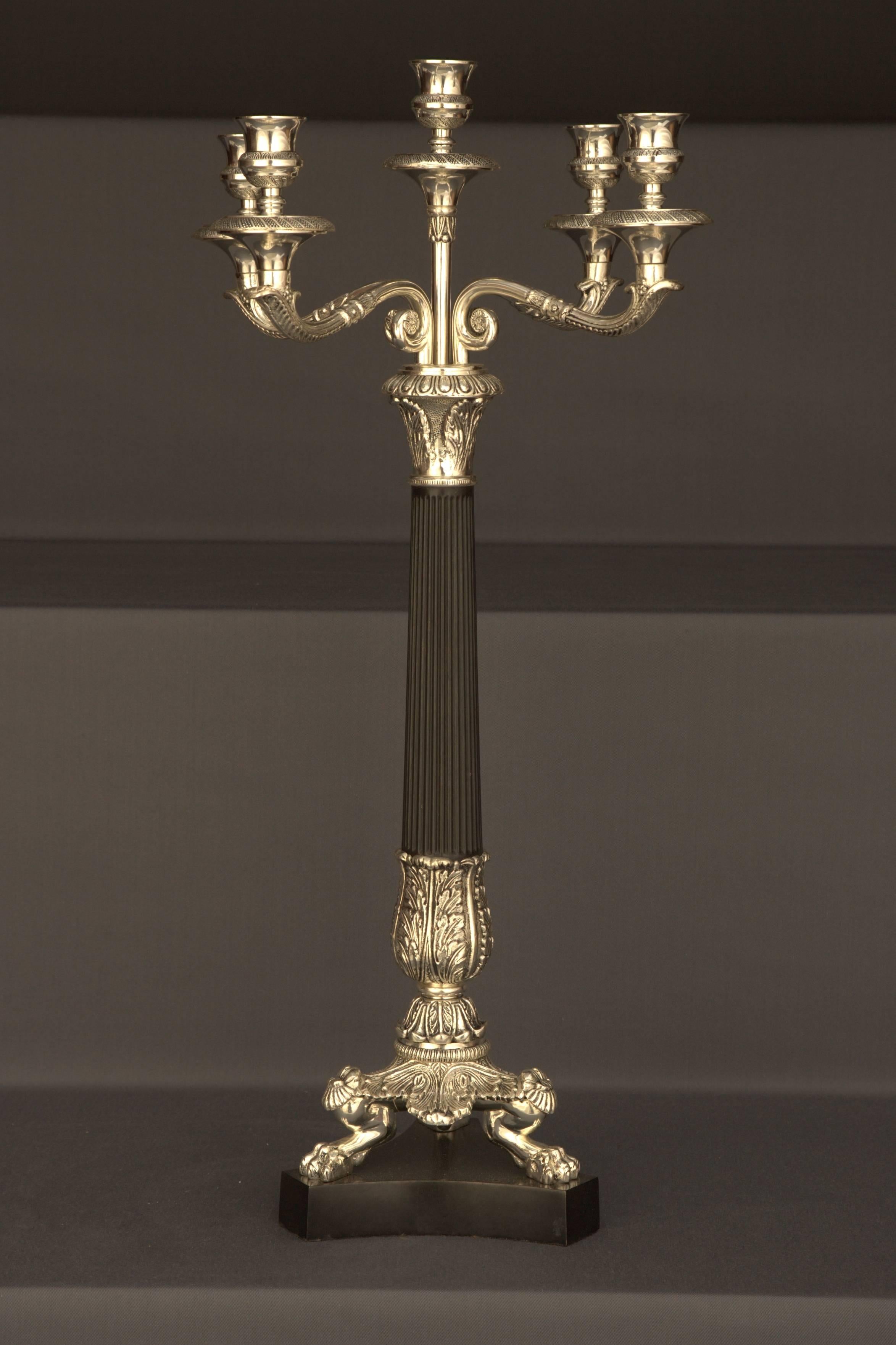 Bronze, finely engraved and silvered. Chanelled columns with
black patination, as holder for four sweeping candelabra arms.
Measures: 
Diameter 33cm, 
height 62cm.