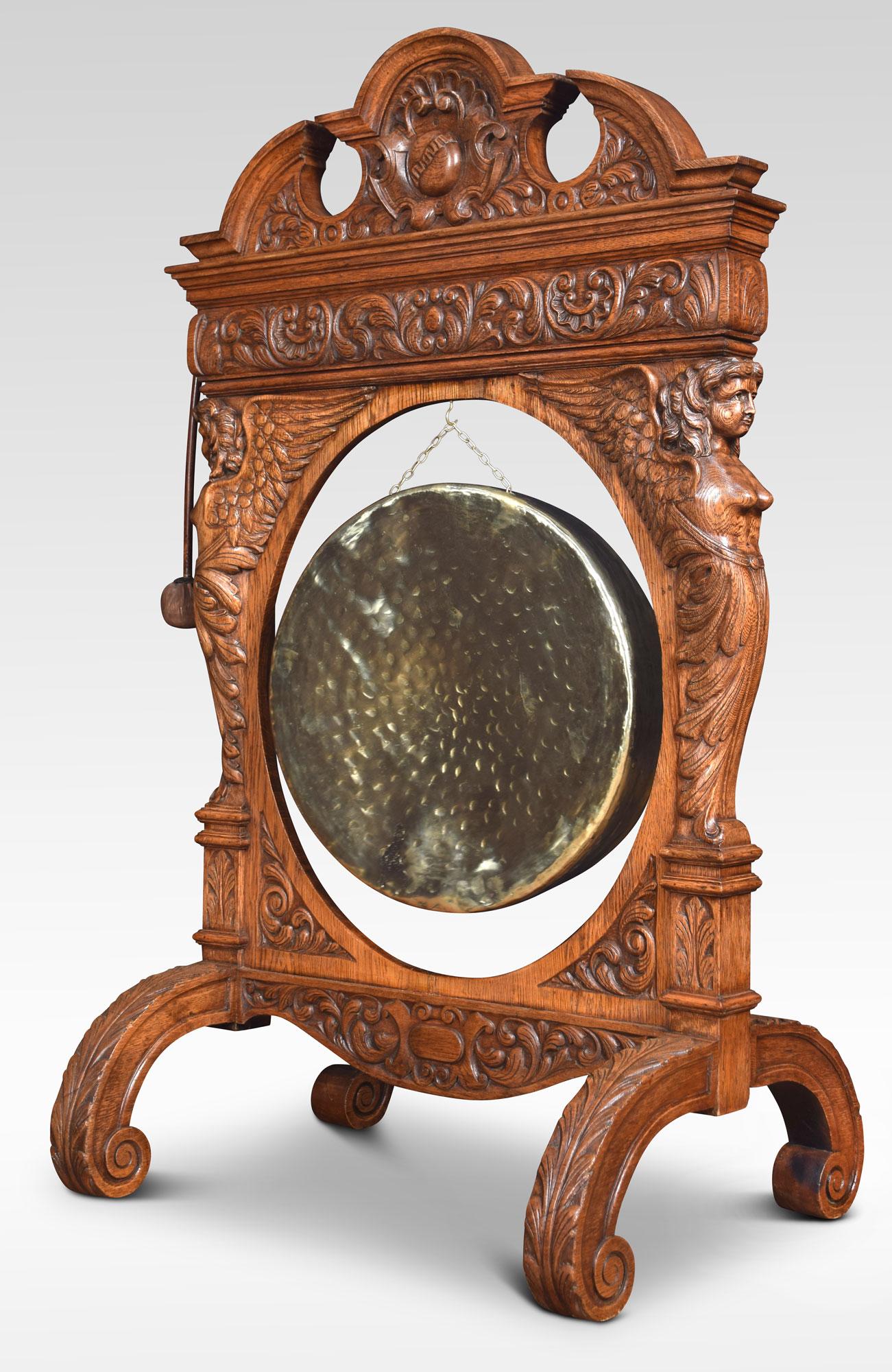 An enormous carved oak dinner gong, the oak frame with swan neck pediment above a leaf carved scroll decorated frame supporting the original brass gong. Flanked by caryatid supports. All raised up on splayed legs.
Dimensions
Height 60