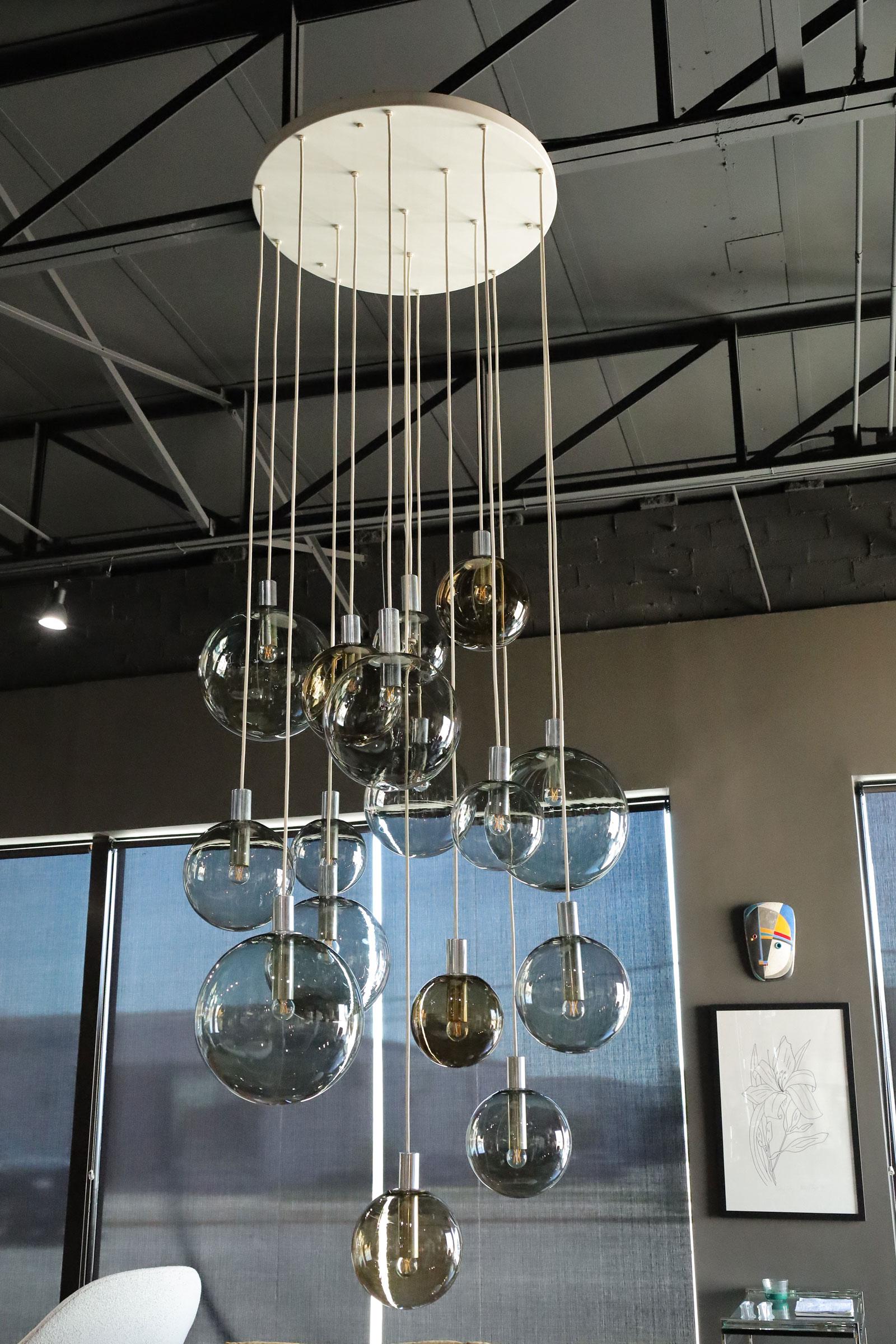 Monumentale lampadario a cascata a 16 globi di Lightolier, circa anni '70. Lampadine in vetro soffiato di varie dimensioni scendono a cascata per quasi 3 metri da un baldacchino rotondo di 32 pollici e creano un'illuminazione di grande effetto per