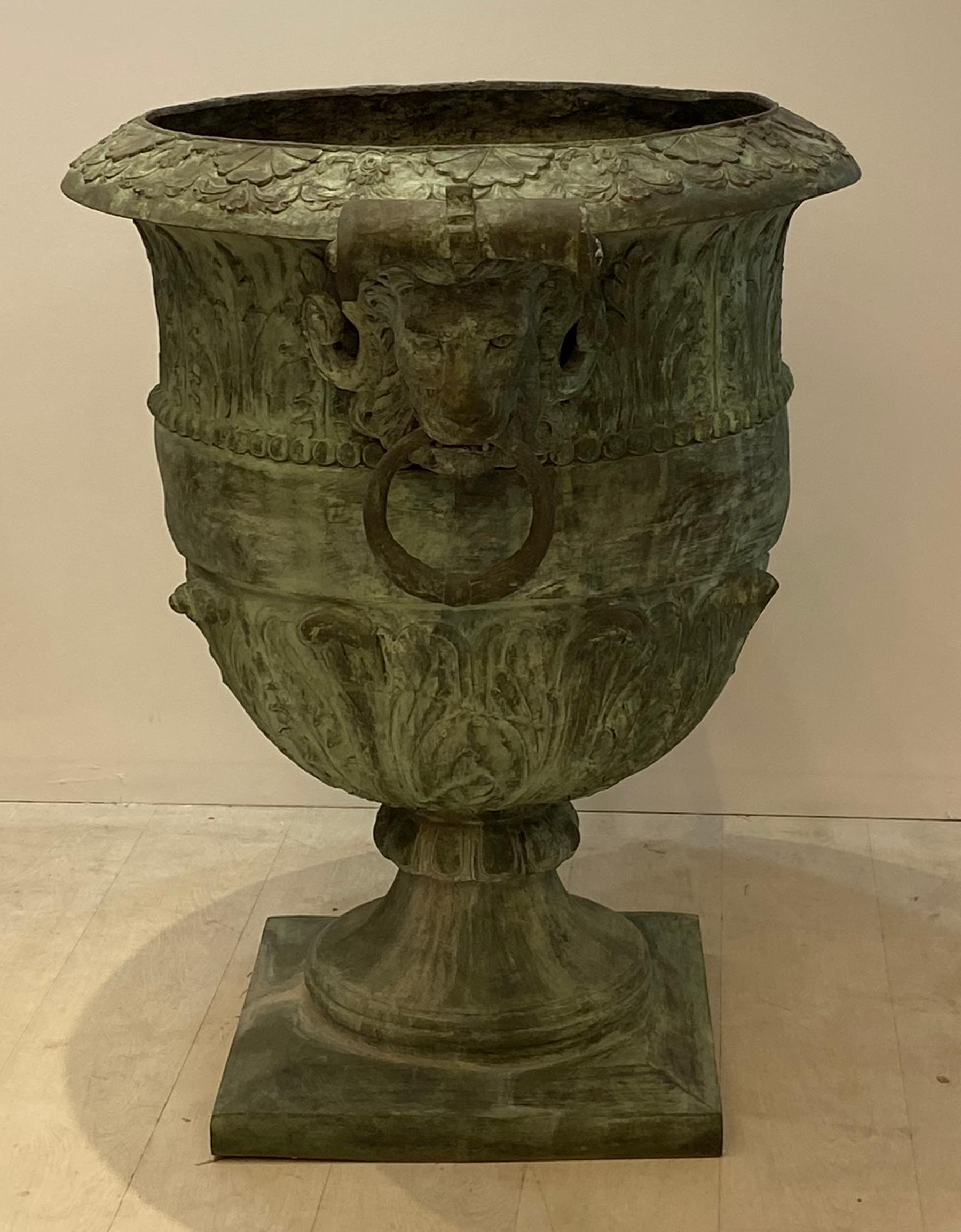 Cast bronze planter with lions head handles. Ornate casting on this large urn with good definition. Aged green patina from years of sitting outdoors in a garden. From a Miami estate.