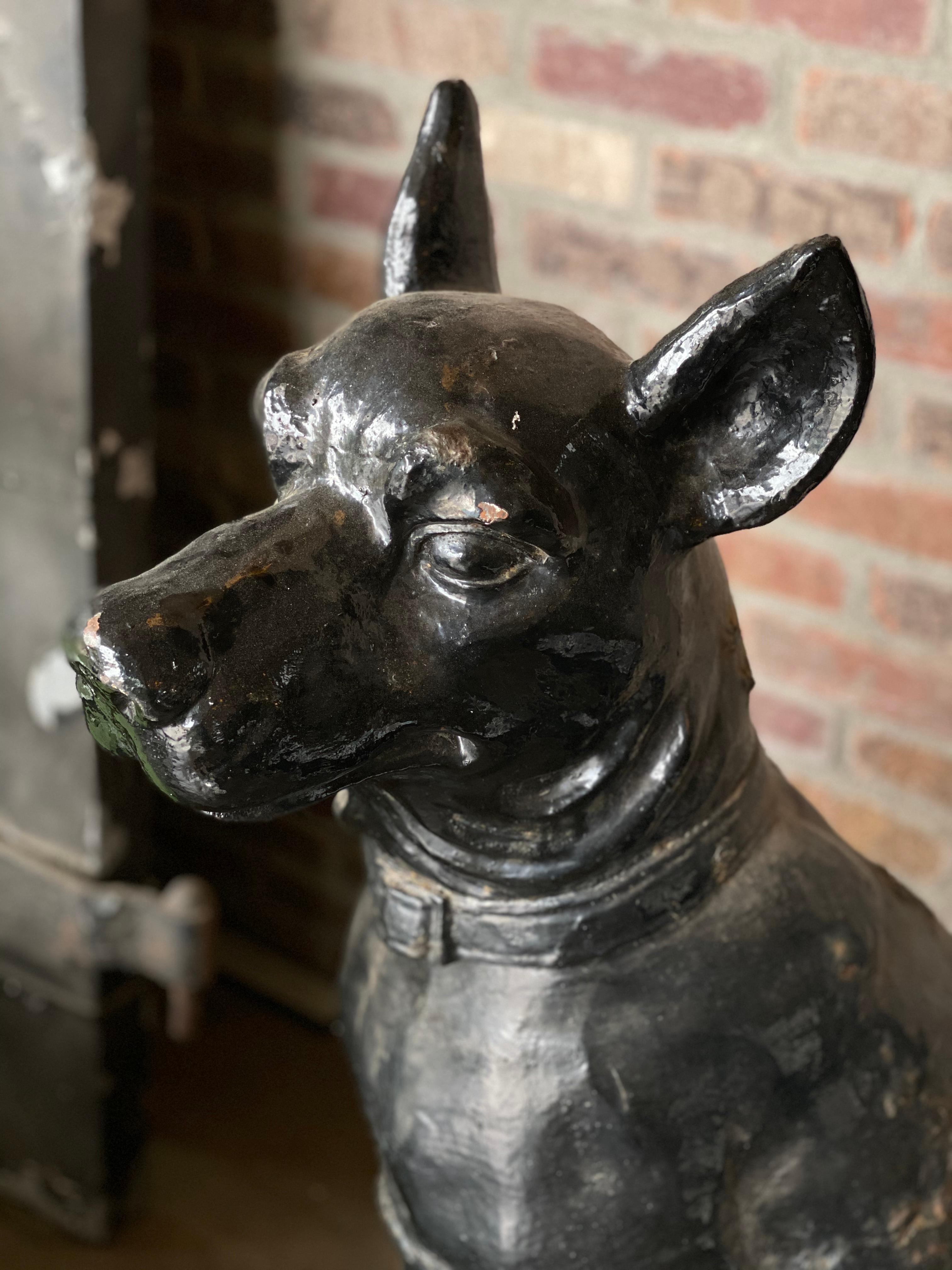 Monumentally scaled 19th century cast iron garden sculptures featuring a pair of dignified dogs with extraordinary presence. Original black painted finish is in good condition, with authentic age. Heads and tails are on opposite sides, with the