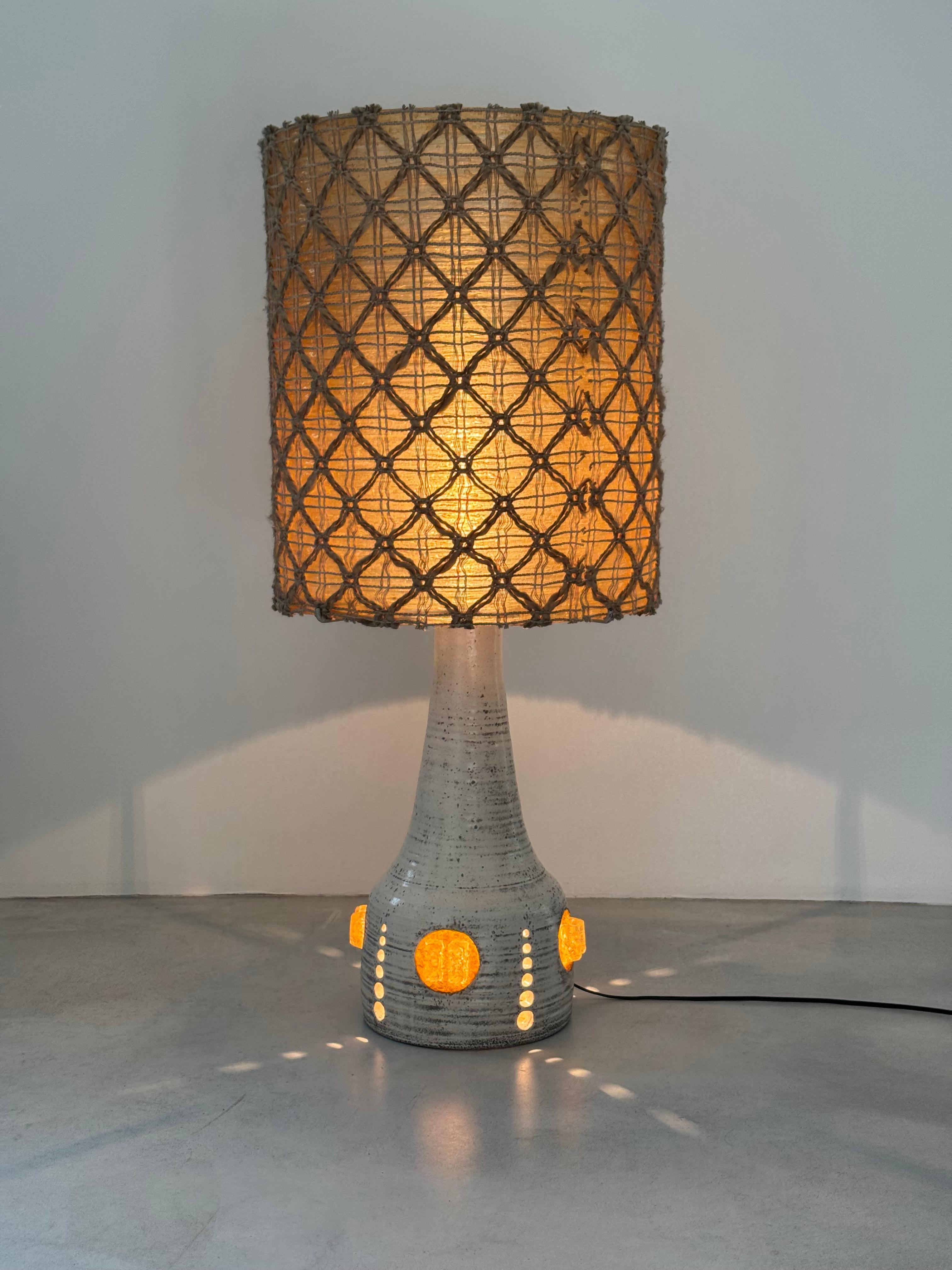 Discover this magnificent and rare floor or table lamp, a sculptural piece by the celebrated Potiers d'Accolay from the 1970s. This impressive lamp stands out with its openwork ceramic base finished in a speckled off-white and gray glaze, giving it