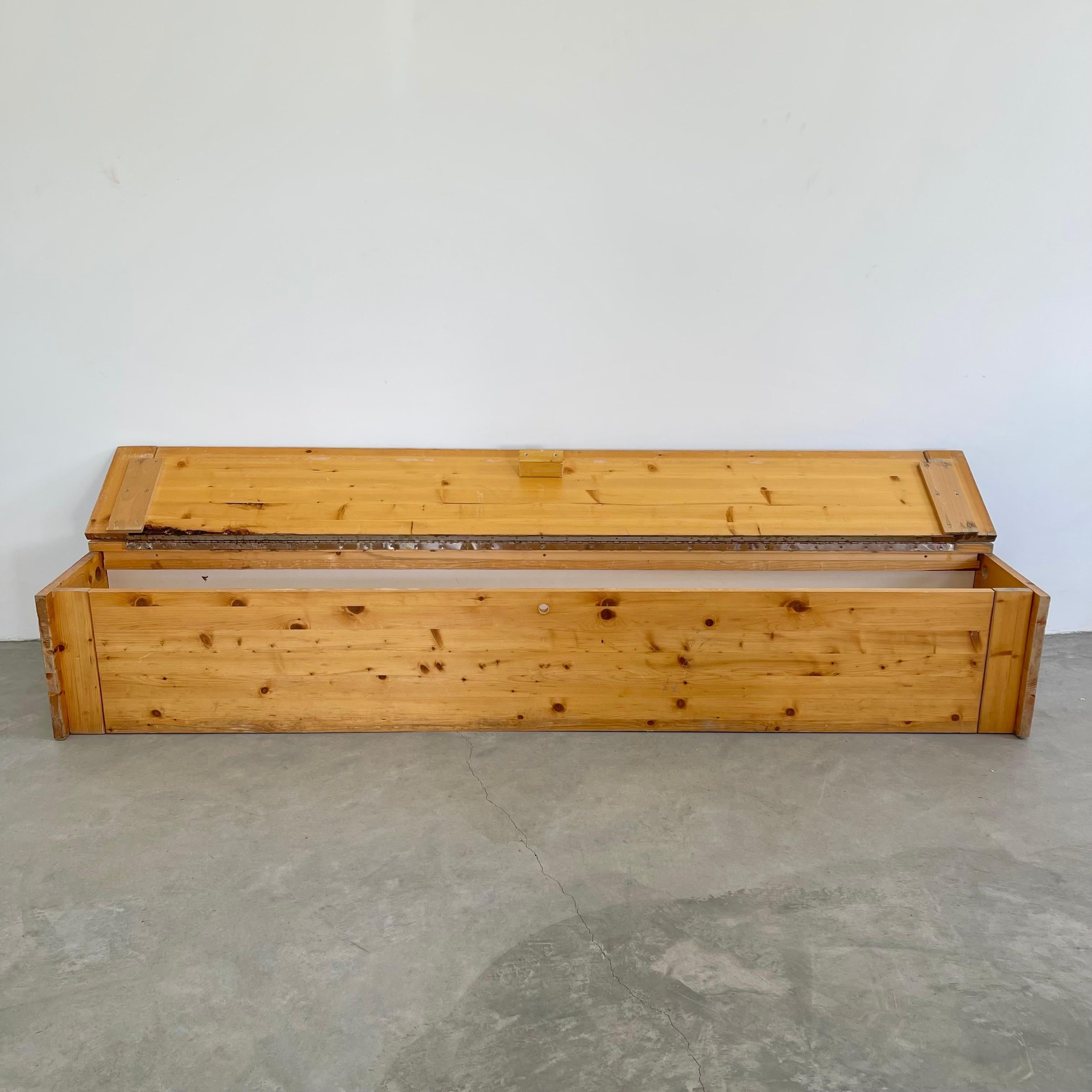 Rare pine storage bench designed by Charlotte Perriand for the Les Arcs Ski Resort in France. Just over 7 feet long. Presently the only one of its kind for sale. Perfect patina to the Pine and an incredibly well preserved white particle board back.