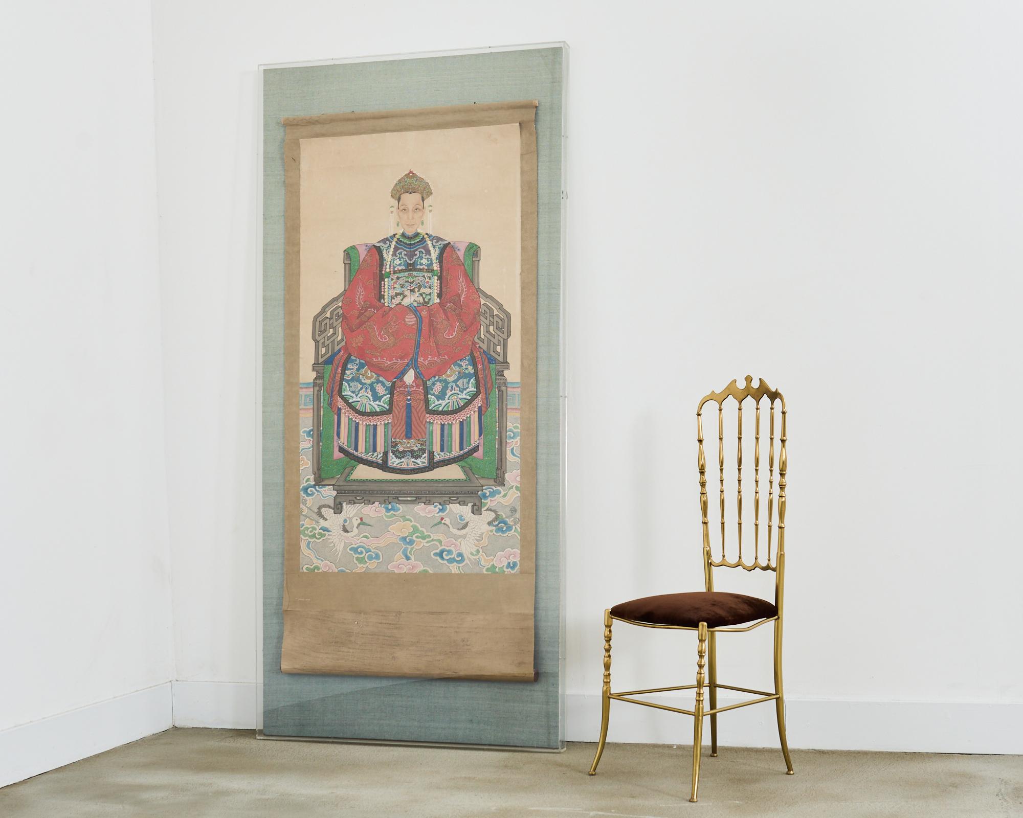 Monumentale dipinto su rotolo di un antenato cinese Qing che ritrae un funzionario di alto rango o una matriarca della corte imperiale. Presenta una matriarca in abito rosso in stile Ming, intricatamente decorata e raffigurata seduta su una sedia in