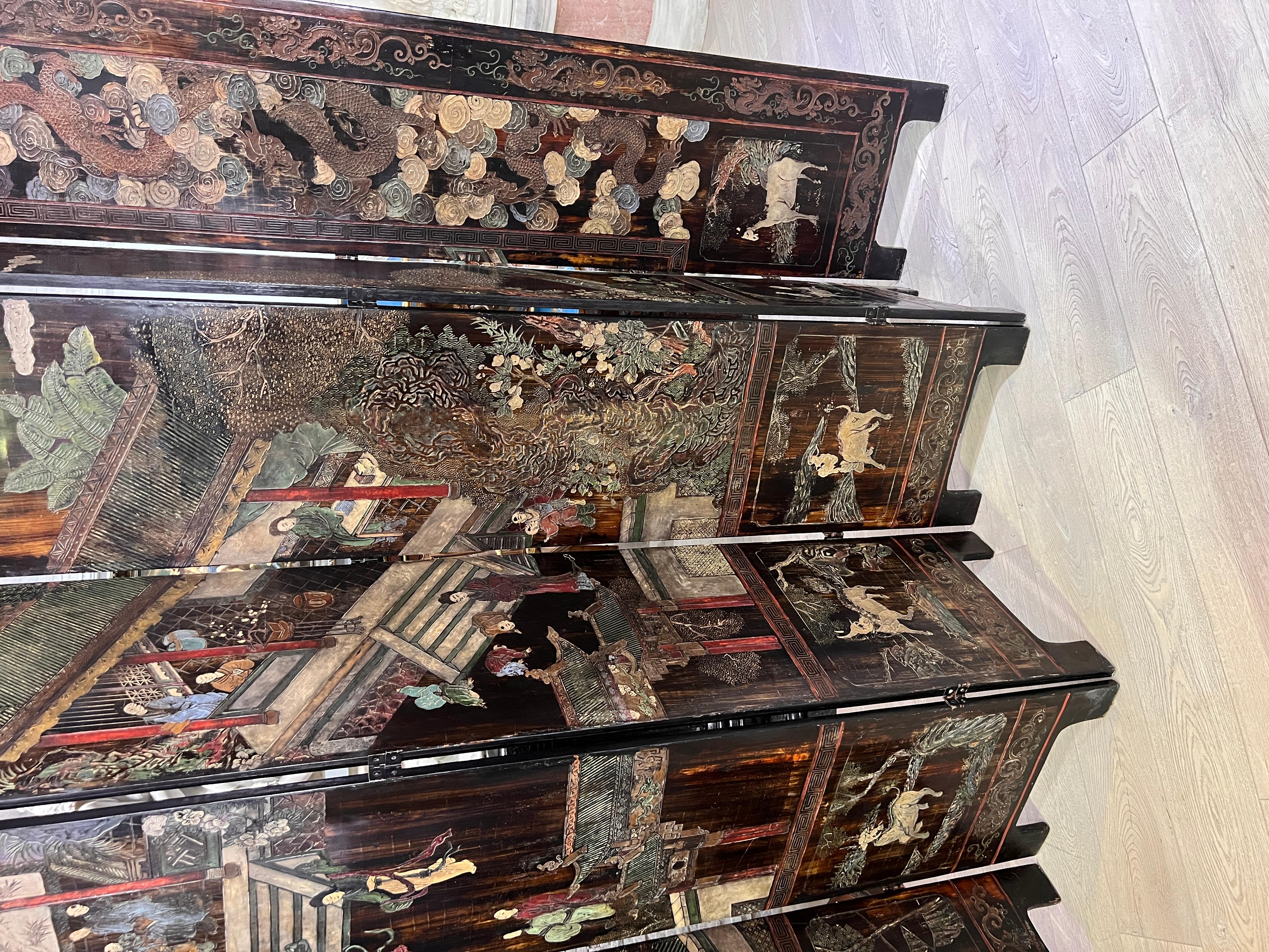 Large and impressive Chinese twelve panel lacquered coromandel screen. This monumental screen features a landscape scene with pavilions and figures Intricately carved and incised with colored pigments. The second panel from right with Chinese