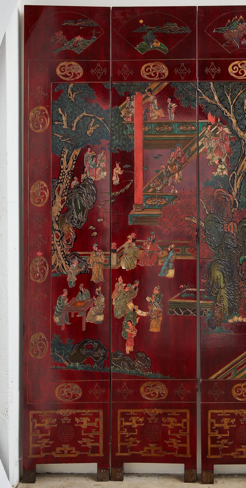 Very impressive monumental Chinese export twelve-panel Coromandel screen depicting a lush courtyard with figures involved in leisurely activities. The panels are incised and lacquered with vibrant colors and gilt over a dramatic dark red background.