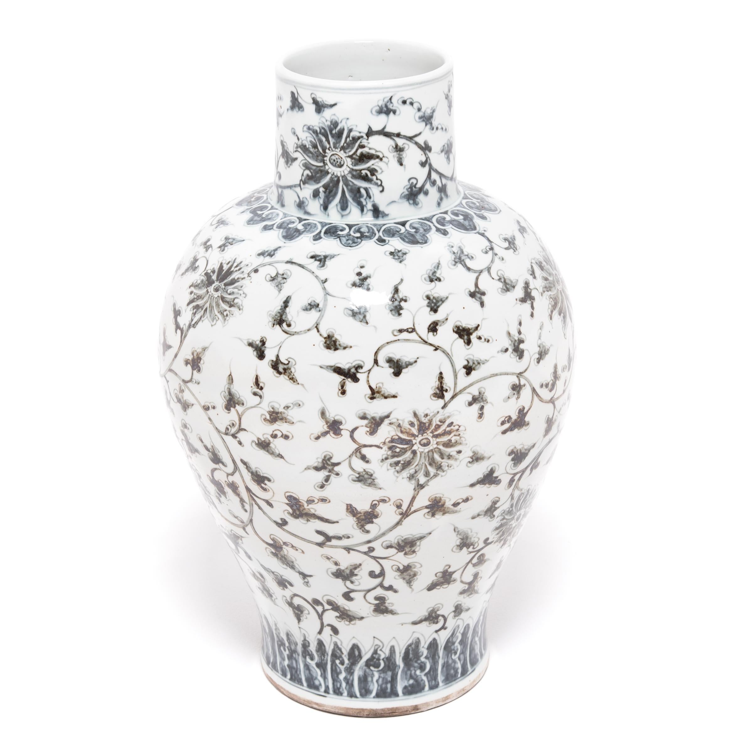Representing royalty and virtue, peonies in full bloom grace the rounded sides of this large porcelain jar. The jar has a tapered body and a cylindrical neck, decorated with a contemporary interpretation of the traditional trailing vine scroll