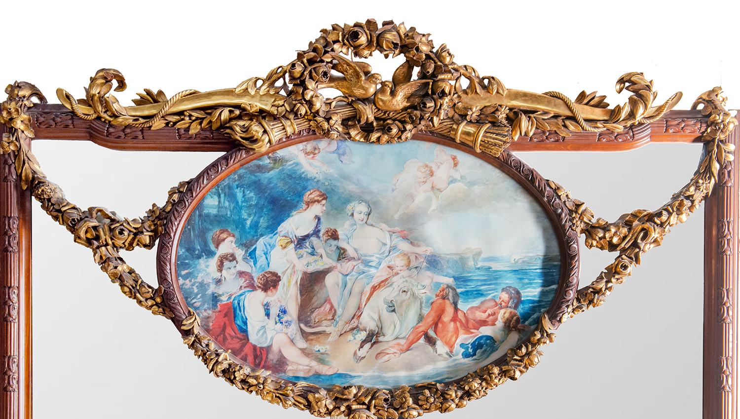 A monumental classical wall mirror, having classical carved foliage, ribbons, birds and a bow and arrows, surrounding a water colour painting depicting 'The Rape of Europa'. The carved mahogany surround frame with reeded and motif decoration.