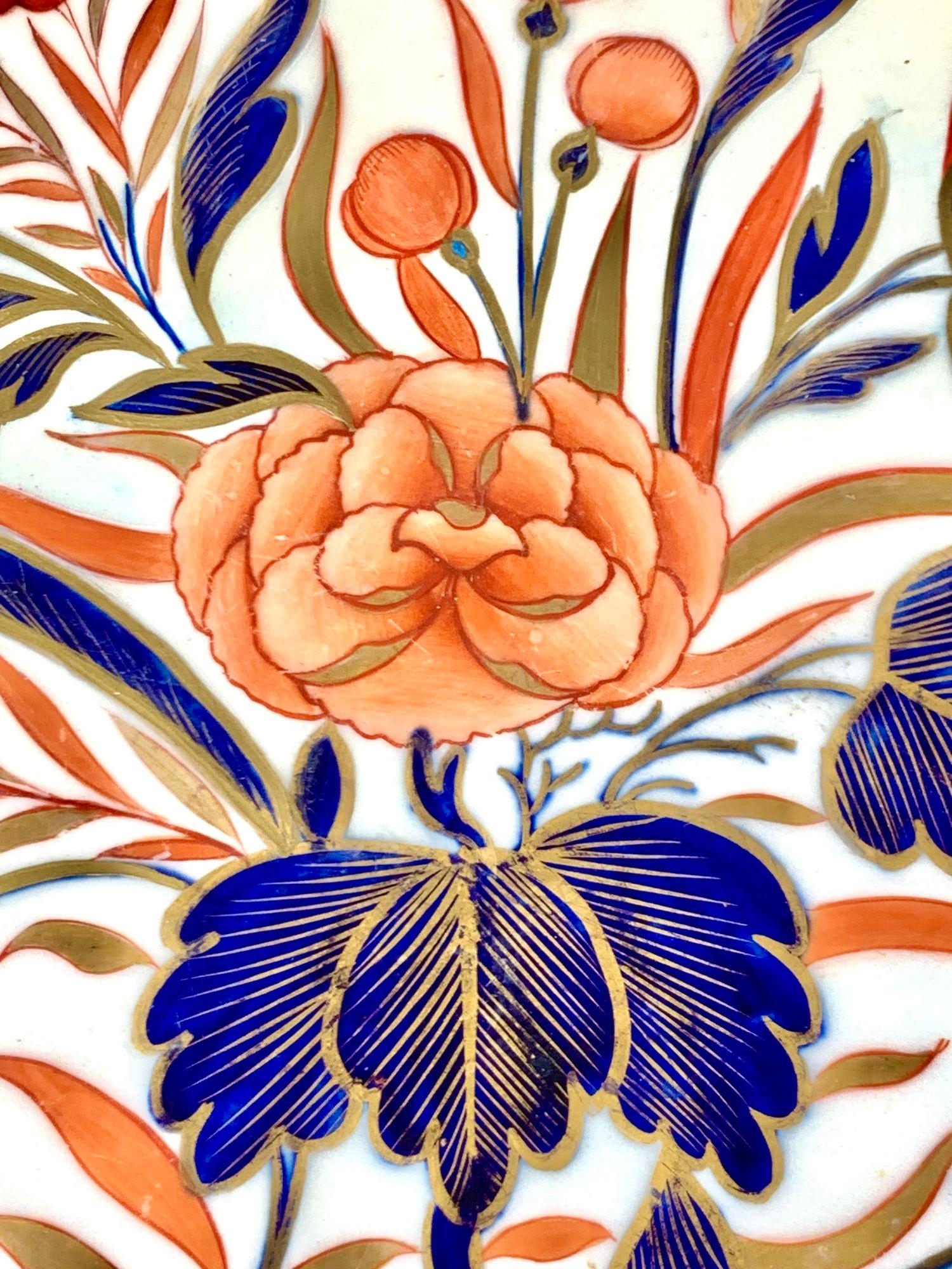 Esta extraordinaria fuente, de 22,25 por 17 pulgadas, ejemplifica la elegante interpretación del estilo Imari del periodo de la Regencia inglesa.
Pintado a mano con grandes peonías de tonos suaves rodeadas de vibrante follaje azul y dorado, el