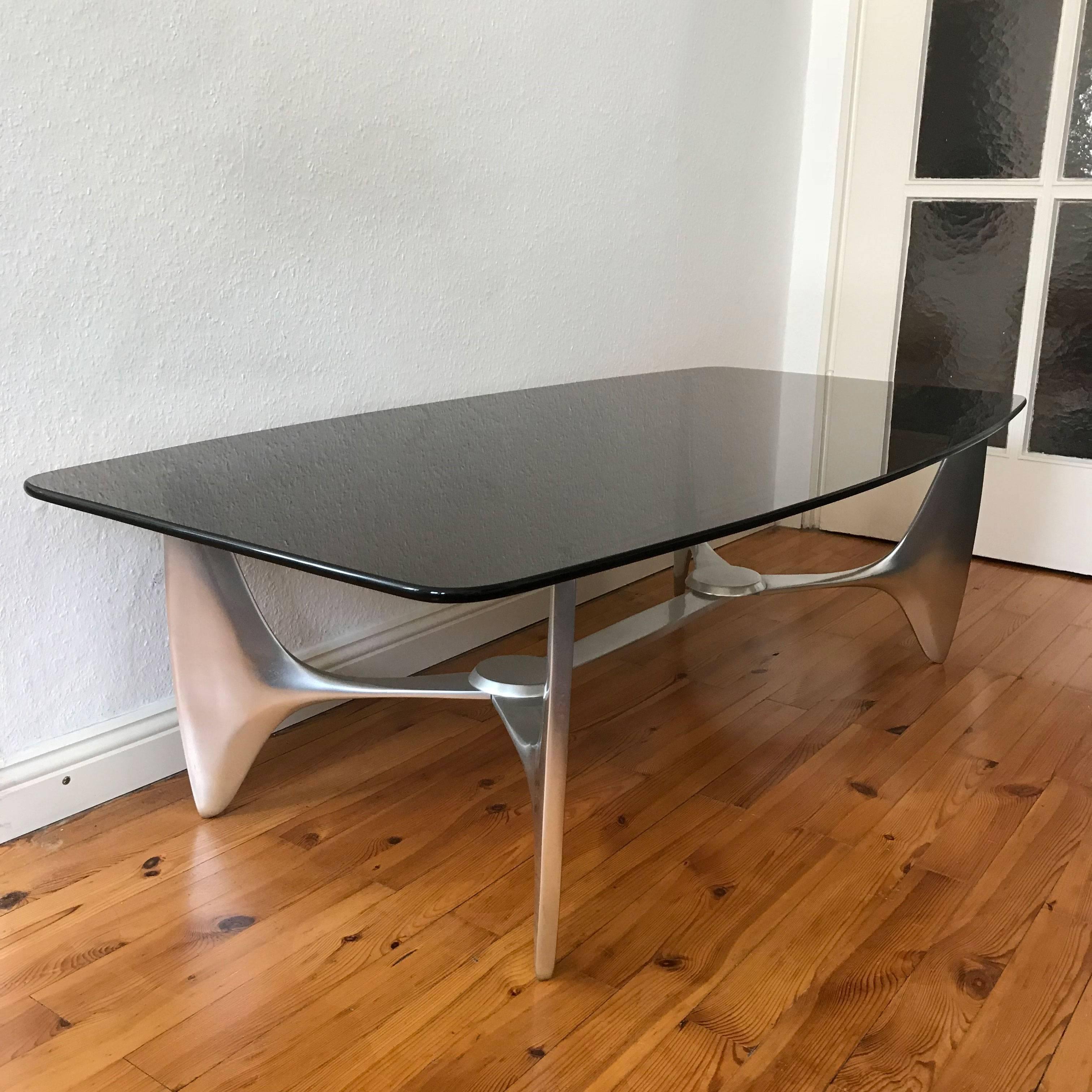 Sculptural Mid-Century Modern coffee or occasional table by Knut Hesterberg for Ronald Schmitt, 1970s, Germany.

This large and exceptional coffee table is executed with a cast aluminium base and smoked glass plate which is ca. 1.5 cm