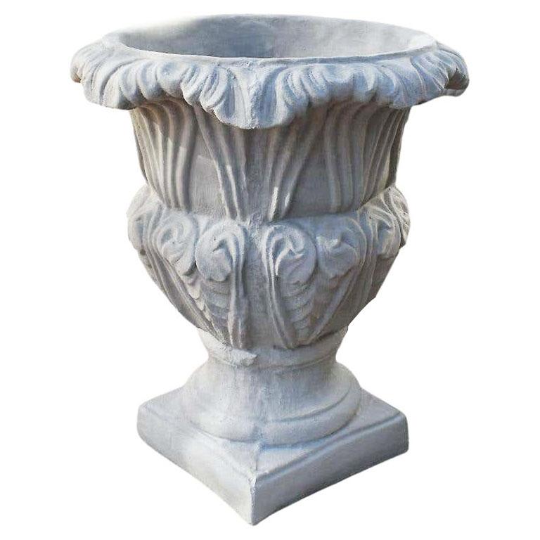 Una coppia monumentale di fioriere o urne da giardino in cemento in stile neoclassico. I bordi di ognuno sono in stile trompe l'oeil e danno l'illusione di un tessuto increspato. I lati del corpo sono decorati con foglie di cemento sporgenti. Questo