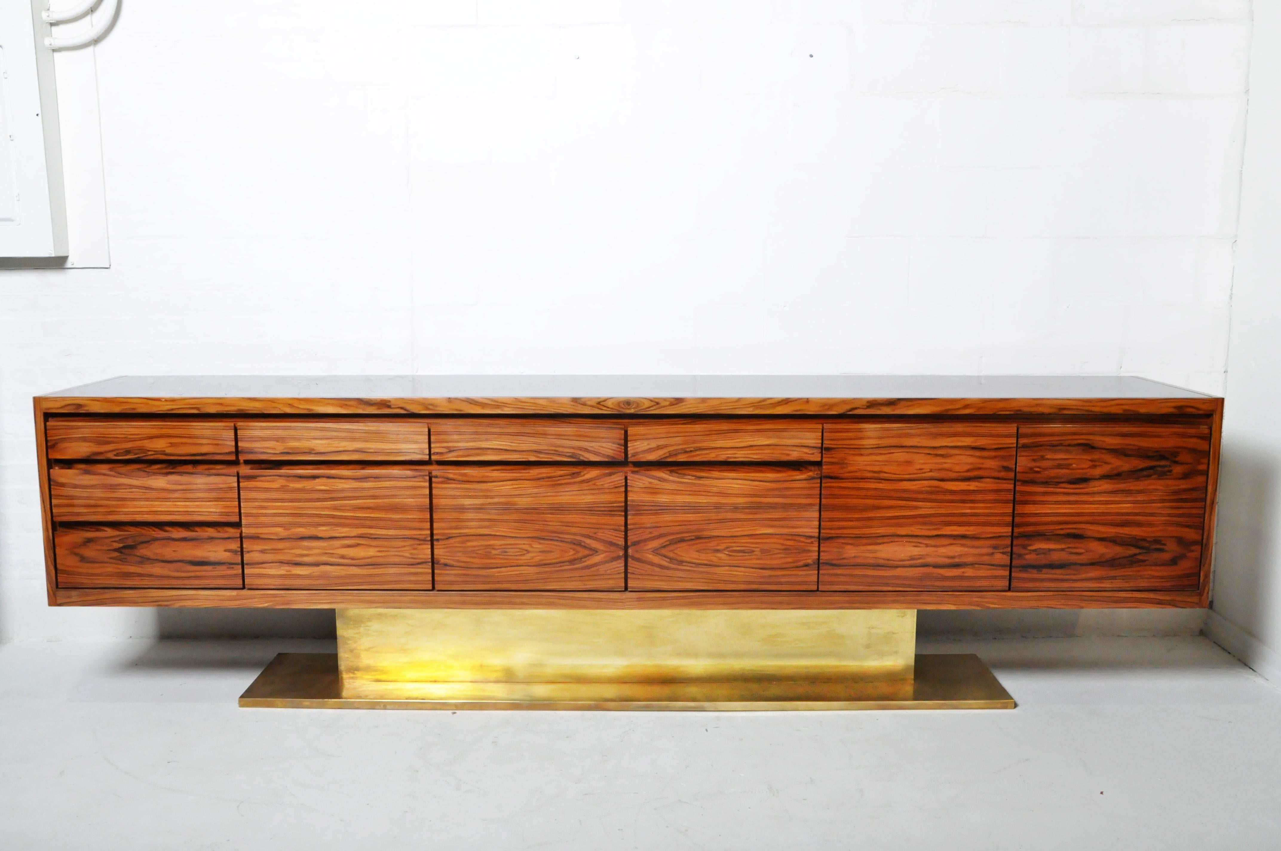 This exceptionally long and sleek console is made from walnut veneers, has a brass base and black glass top. It is a Hungarian-made recreation of a vintage French mid-century modern sideboard design. Special attention has been given to the selection